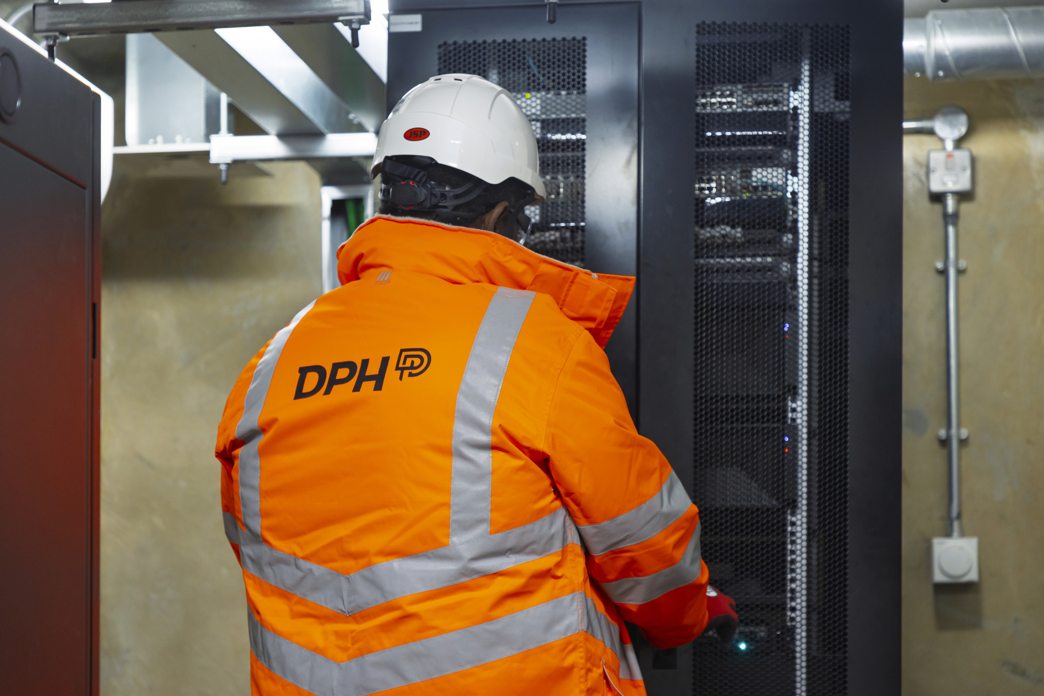 Modern glass building with illuminated interior and reflections at sunset