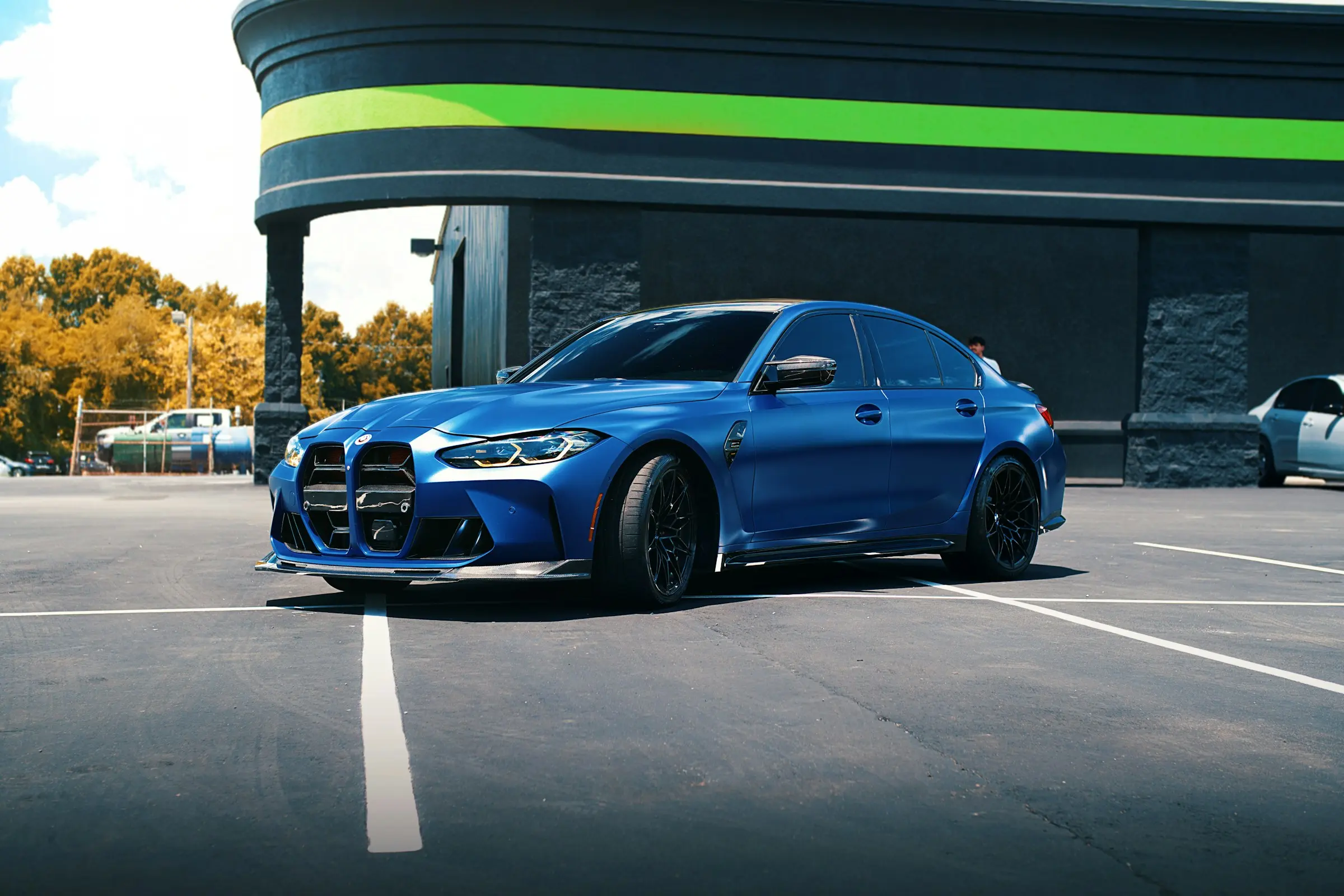 Blue sports sedan parked in front of a modern car dealership building