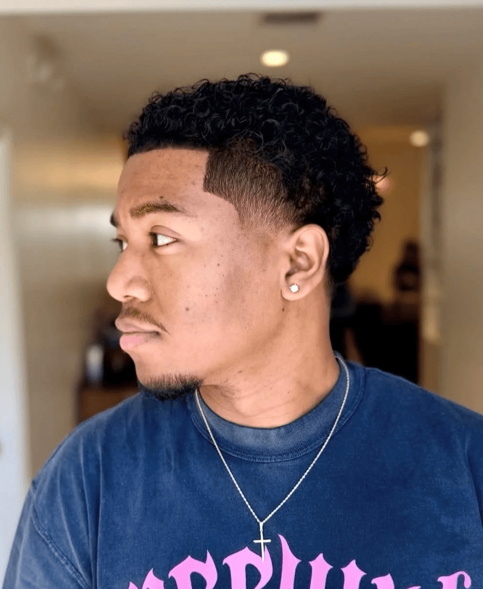 Classic mid taper fade for men, highlighting a natural hairline and youthful styling on curly hair by Courtney Palmore. Sharp Line Up