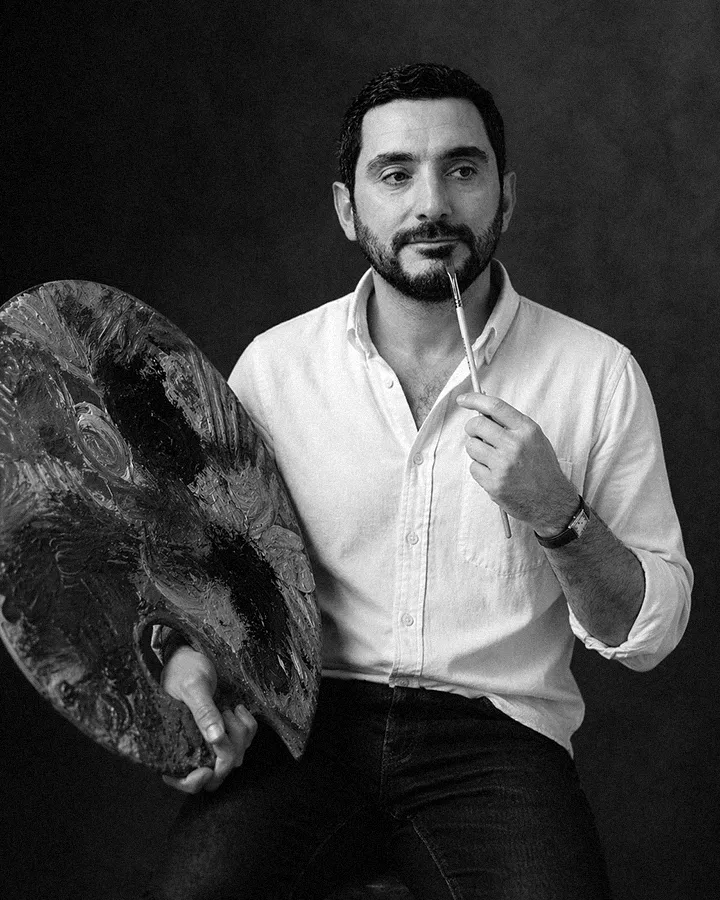 A thoughtful young person with dark hair gazes to the side, captured in soft black and white lighting.