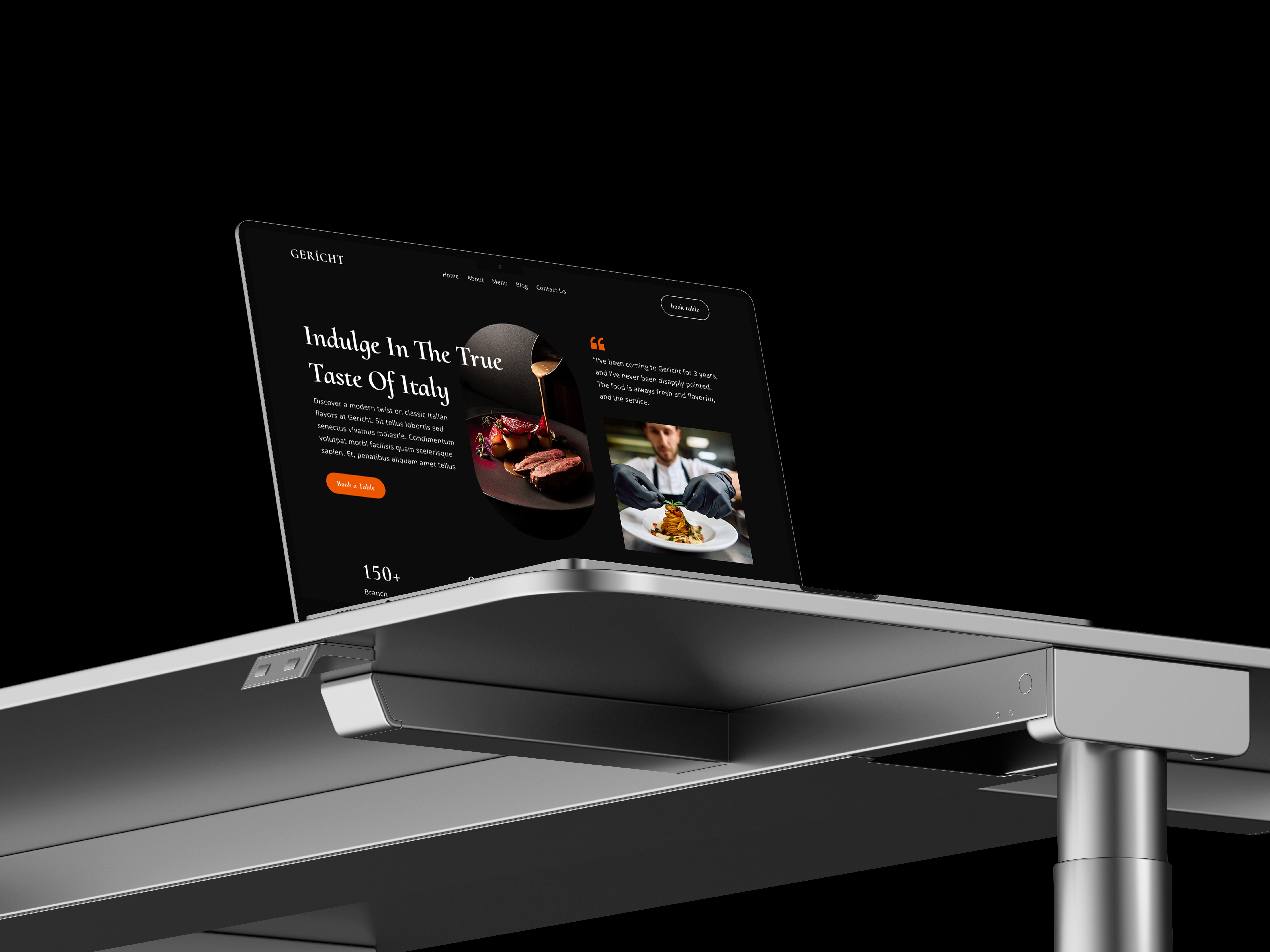 Laptop displaying a restaurant website on a modern standing desk. The website features images of Italian food and a chef.
