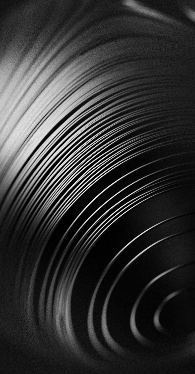 Close-up of concentric grooves curving across the frame in black and white, evoking the form of recorded sound.