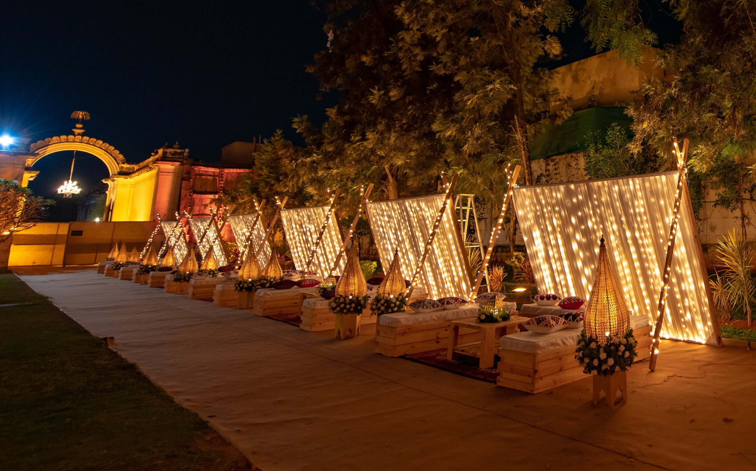 A person kneads fresh dough on a wooden kitchen counter dusted with flour, with pottery and a plant visible in the background, evoking a rustic baking atmosphere.