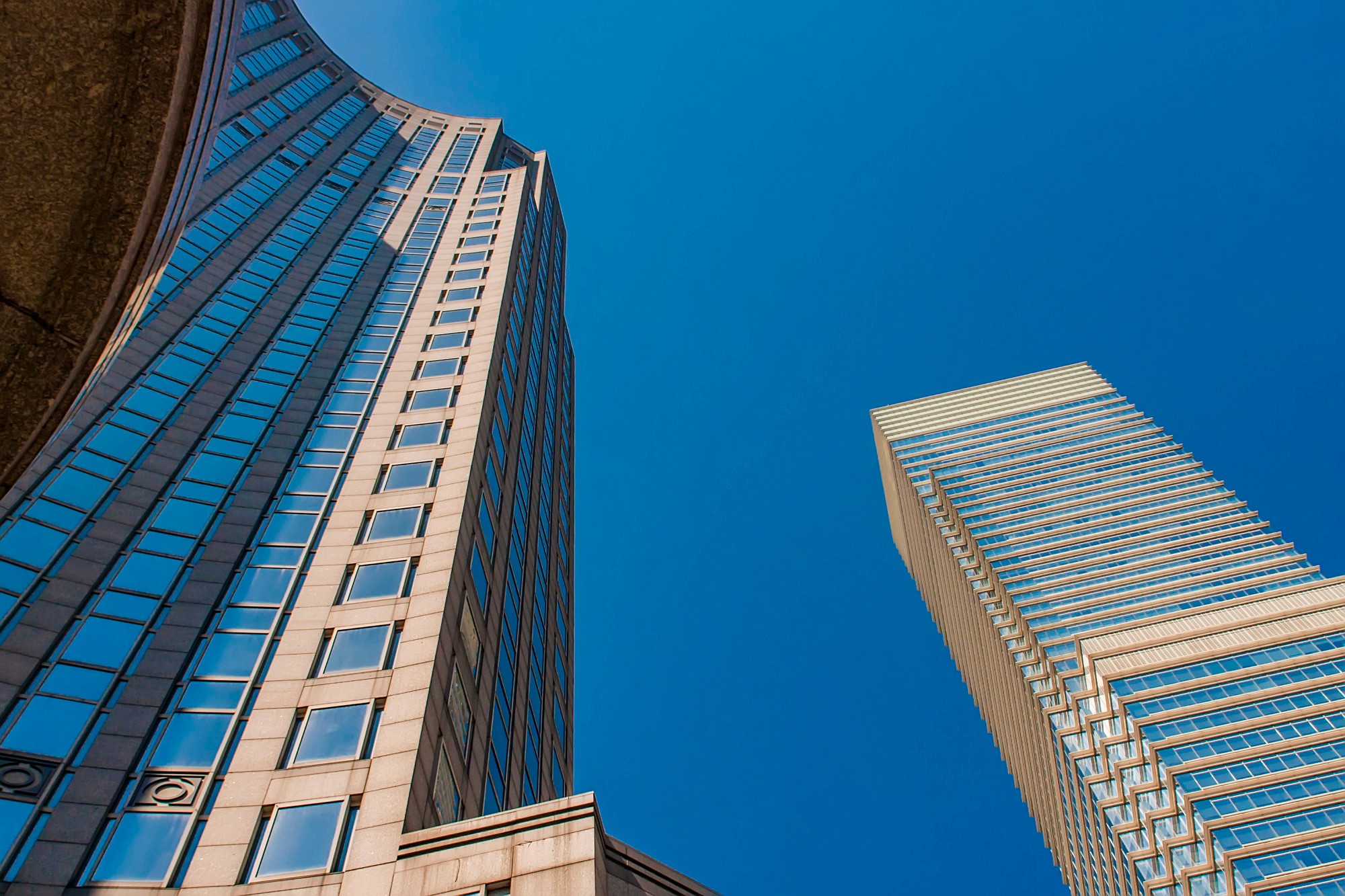 Upward view of two skyscrapers against the sky.