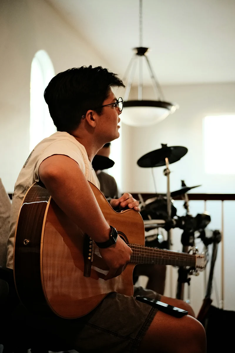 Music teacher guiding an adult guitar student