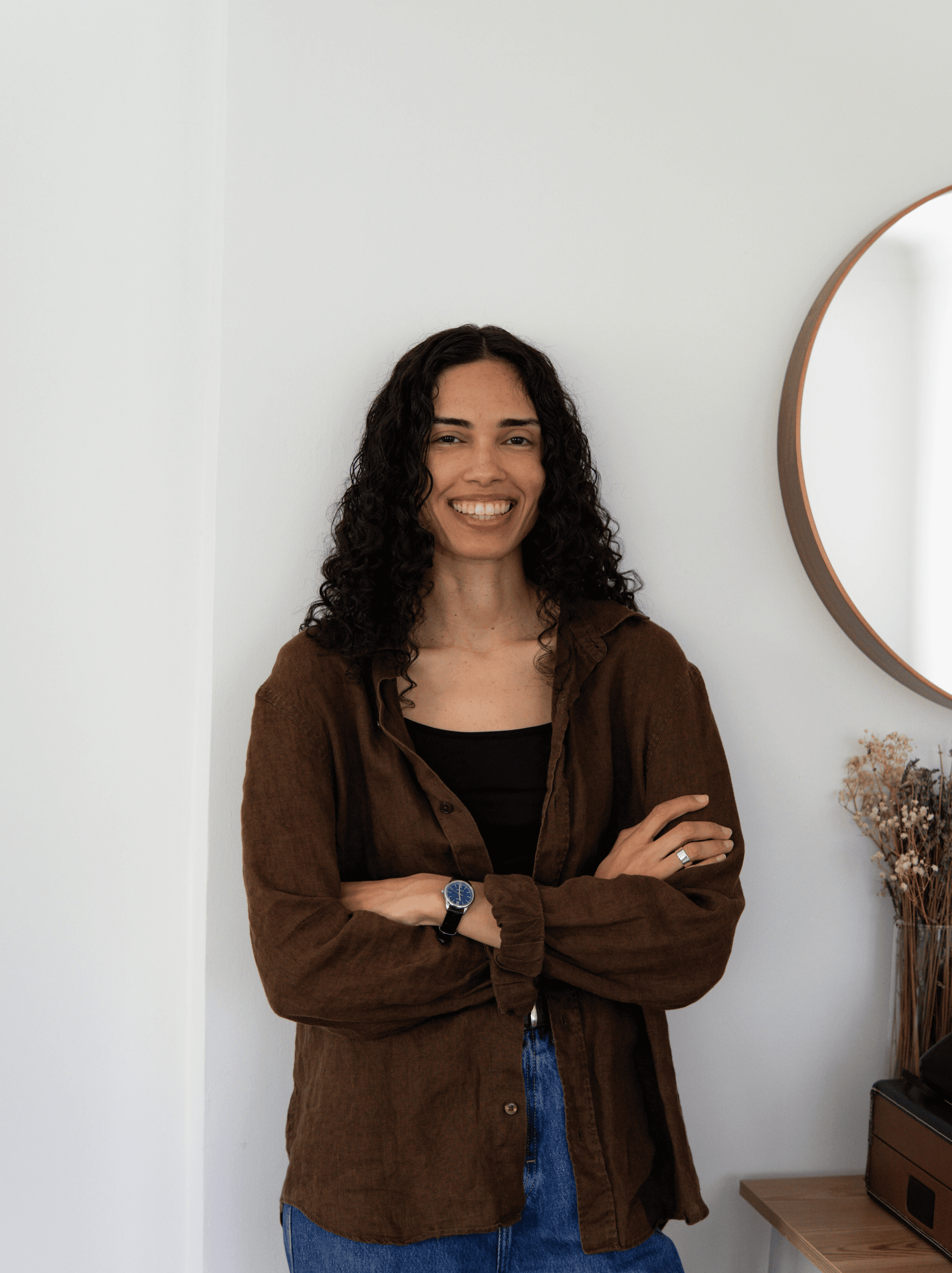 woman standing close to a wall with her arms crossed with a big smile on her face