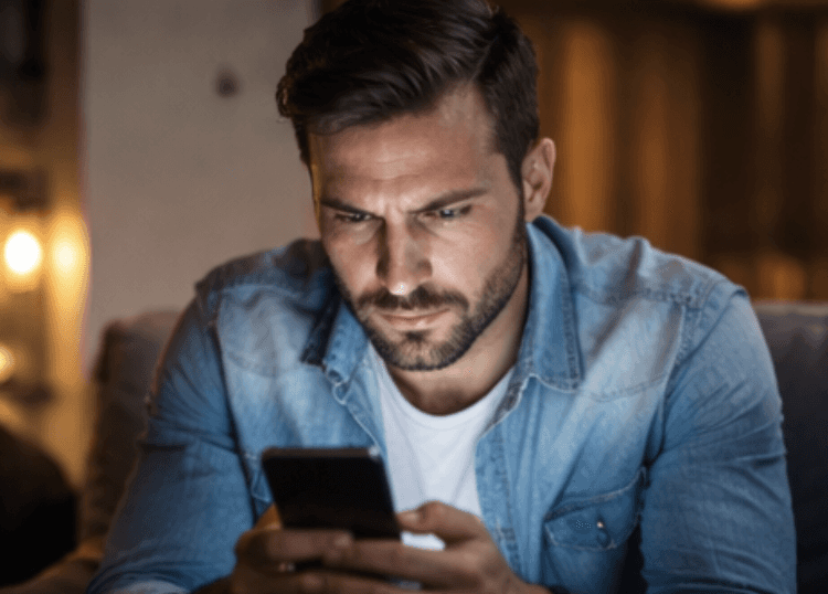 ein mann benutzt sein handy, er sitzt auf einer coach