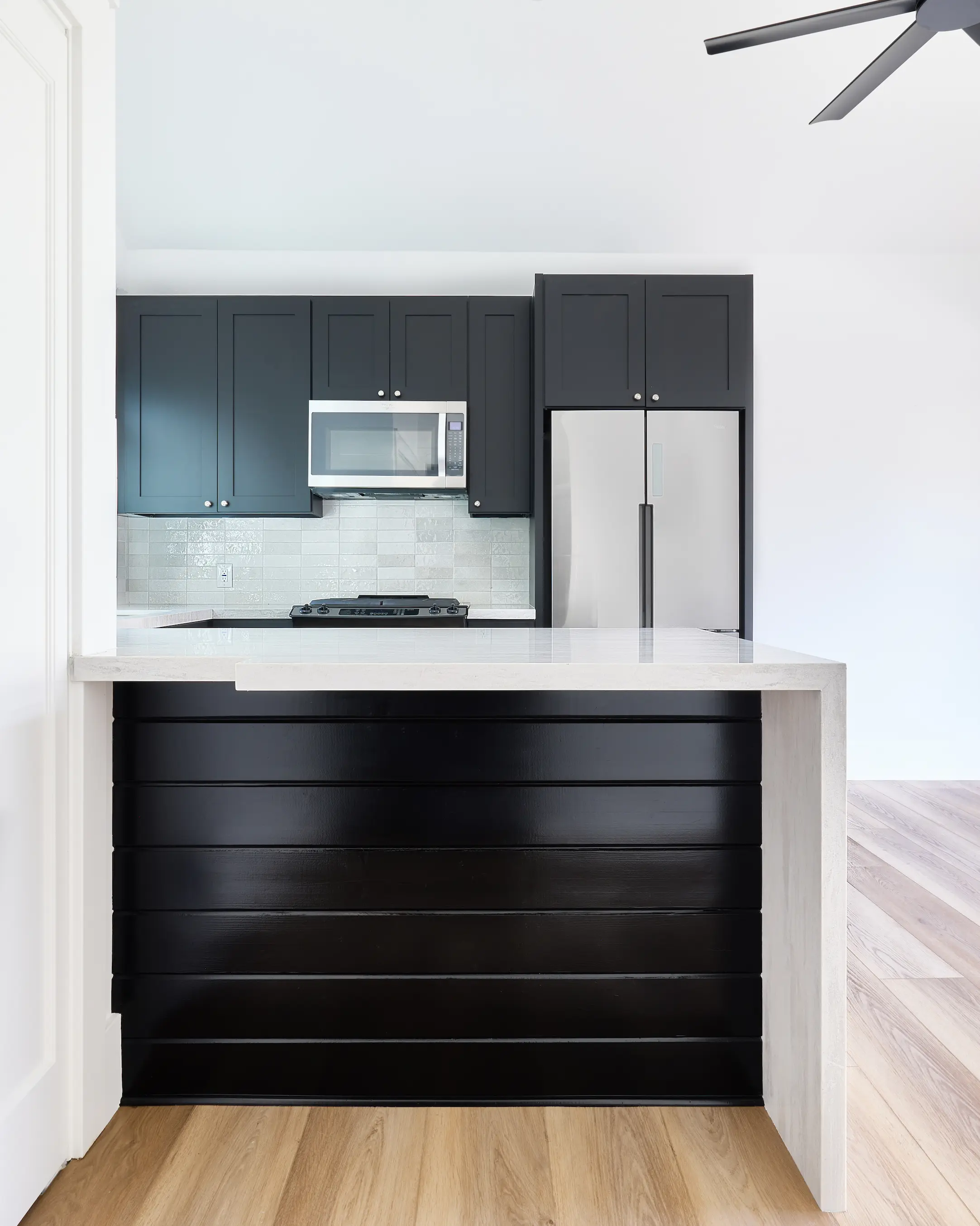 Portrait view from the kitchen's countertop seating area, highlighting the sleek quartz waterfall edge and contemporary finishes. Photo by Todd Huge.