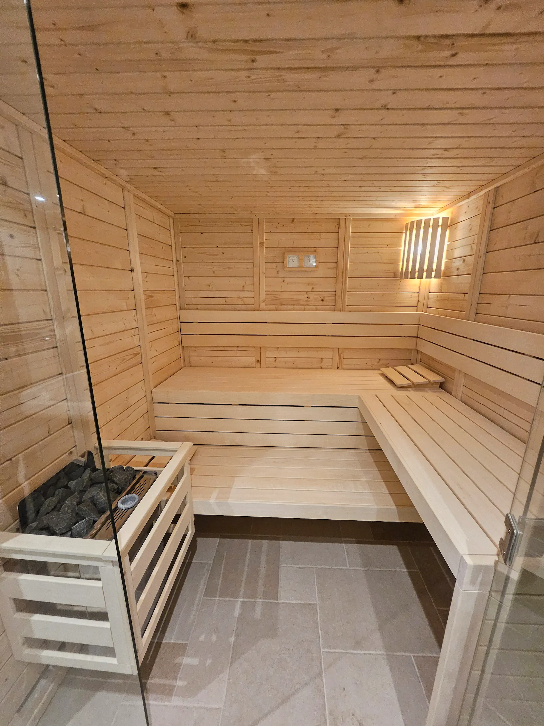 Sauna en bois clair avec pierres chaudes et bancs pour la détente.