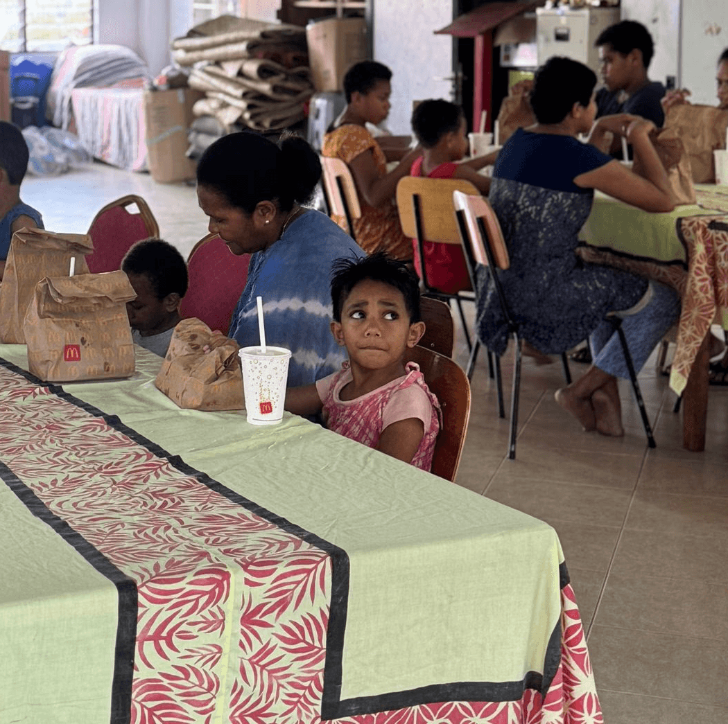 five children smiling while doing peace hand sign