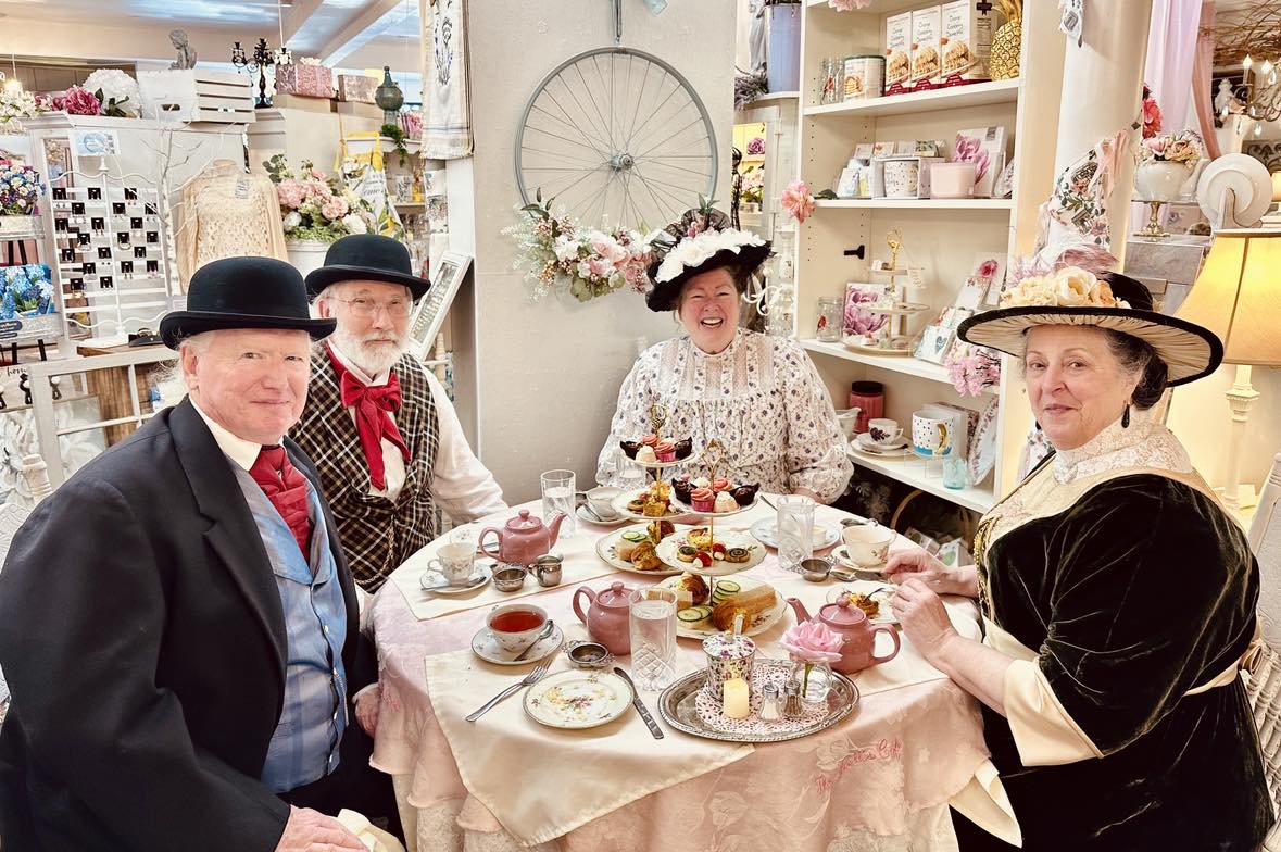 Four fancy people dressed for afternoon high tea at the pink chandelier