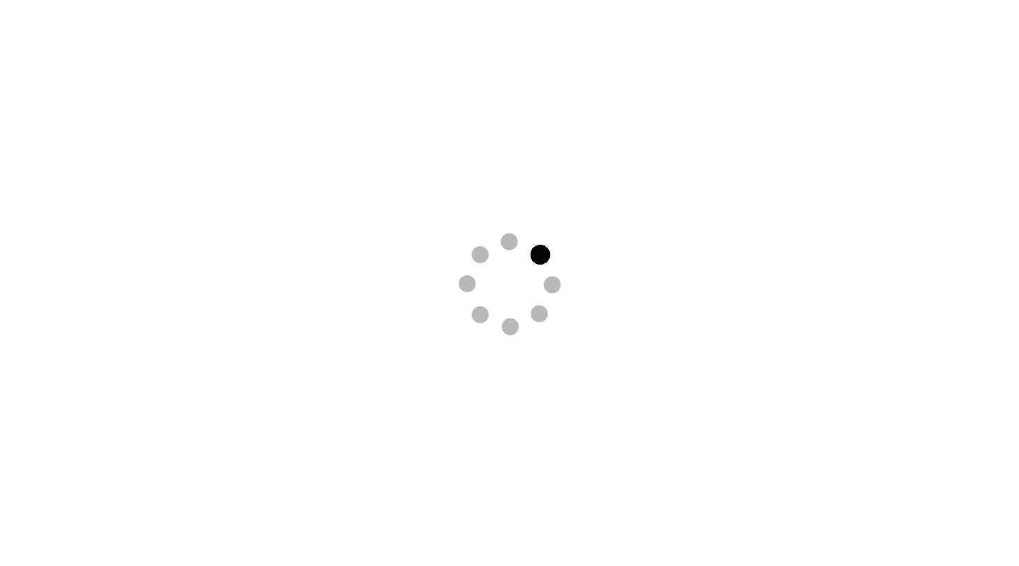 A circular loading indicator with a series of gray dots arranged in a ring. One dot is black, suggesting movement in a clockwise direction to indicate an ongoing process. The design represents a typical spinner used to show that content is loading or a task is in progress.