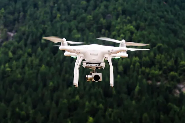 Dron con cámara sobrevolando una zona de bosque, el tipo de vuelo en categoría abierta que determina si el seguro de responsabilidad civil para drones es obligatorio según la normativa AESA en España