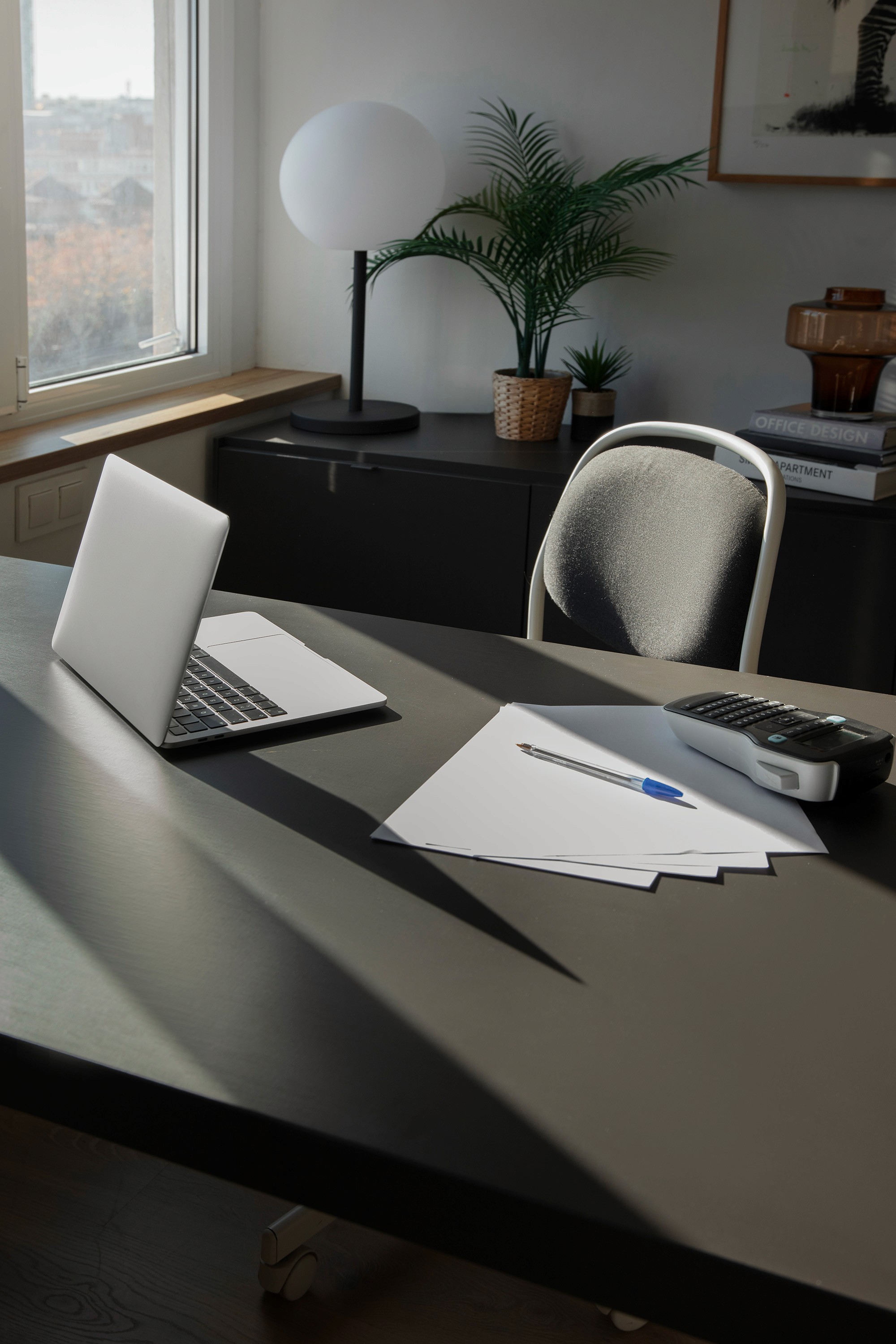 Modern desk with laptop, papers, and potted plants