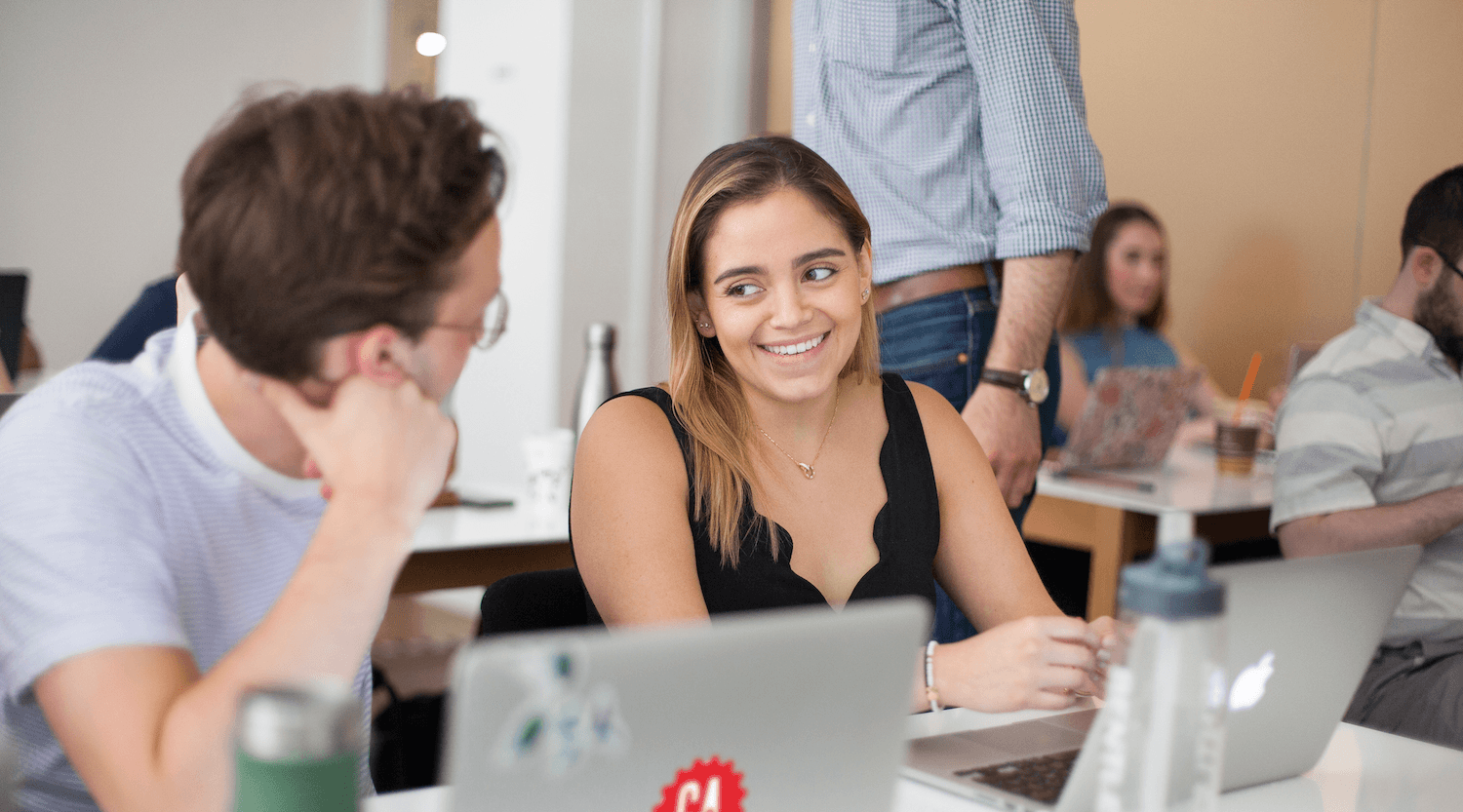 A designer working at a laptop in a clean, well-lit studio setting.
