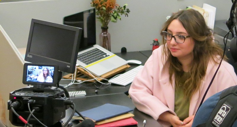 A photo of a group of people filming a scene in an office.