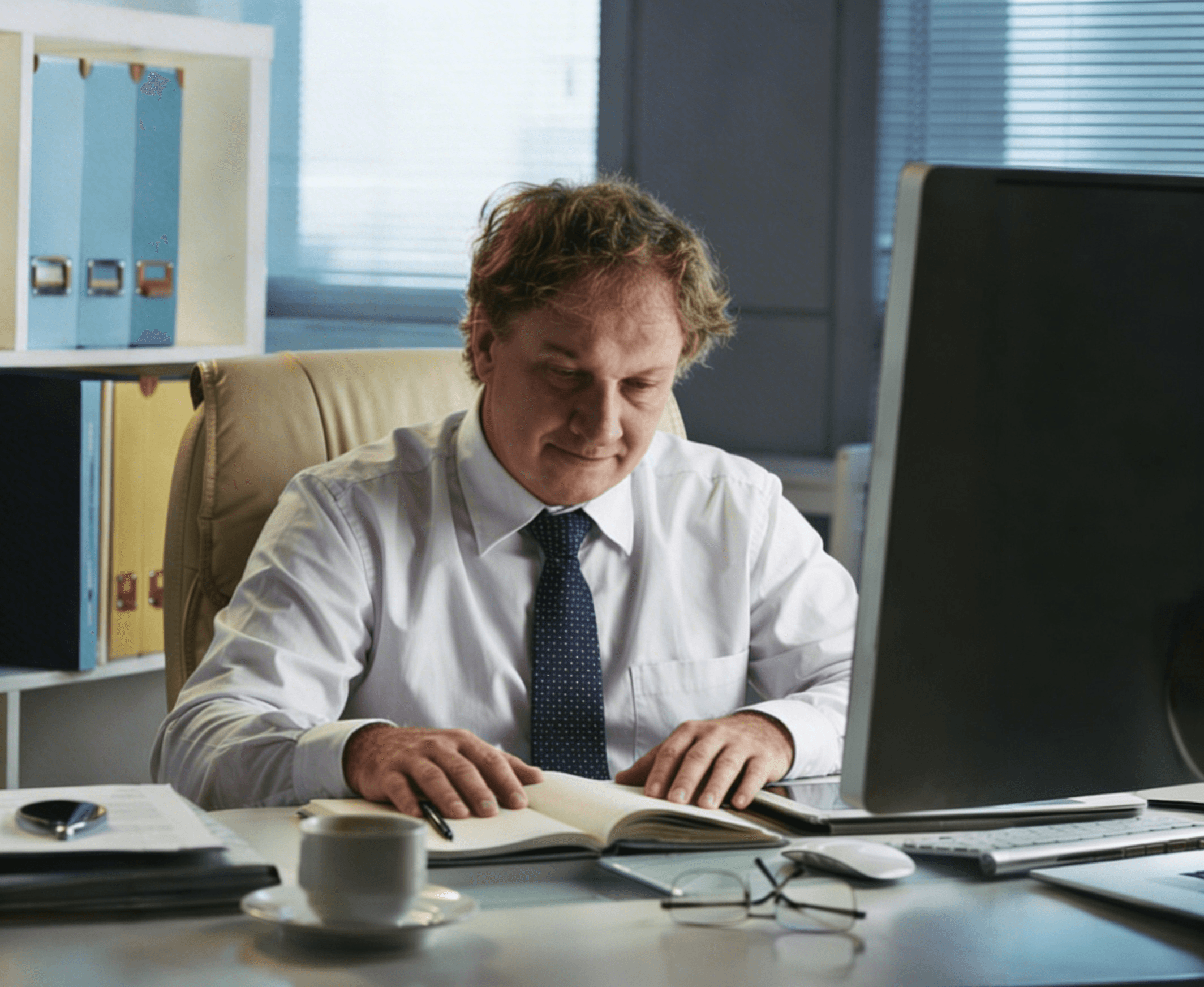 Innendienstler fokussiert am Schreibtisch. er ließt seine Notizen, lächelt leicht und sieht entspannt aus