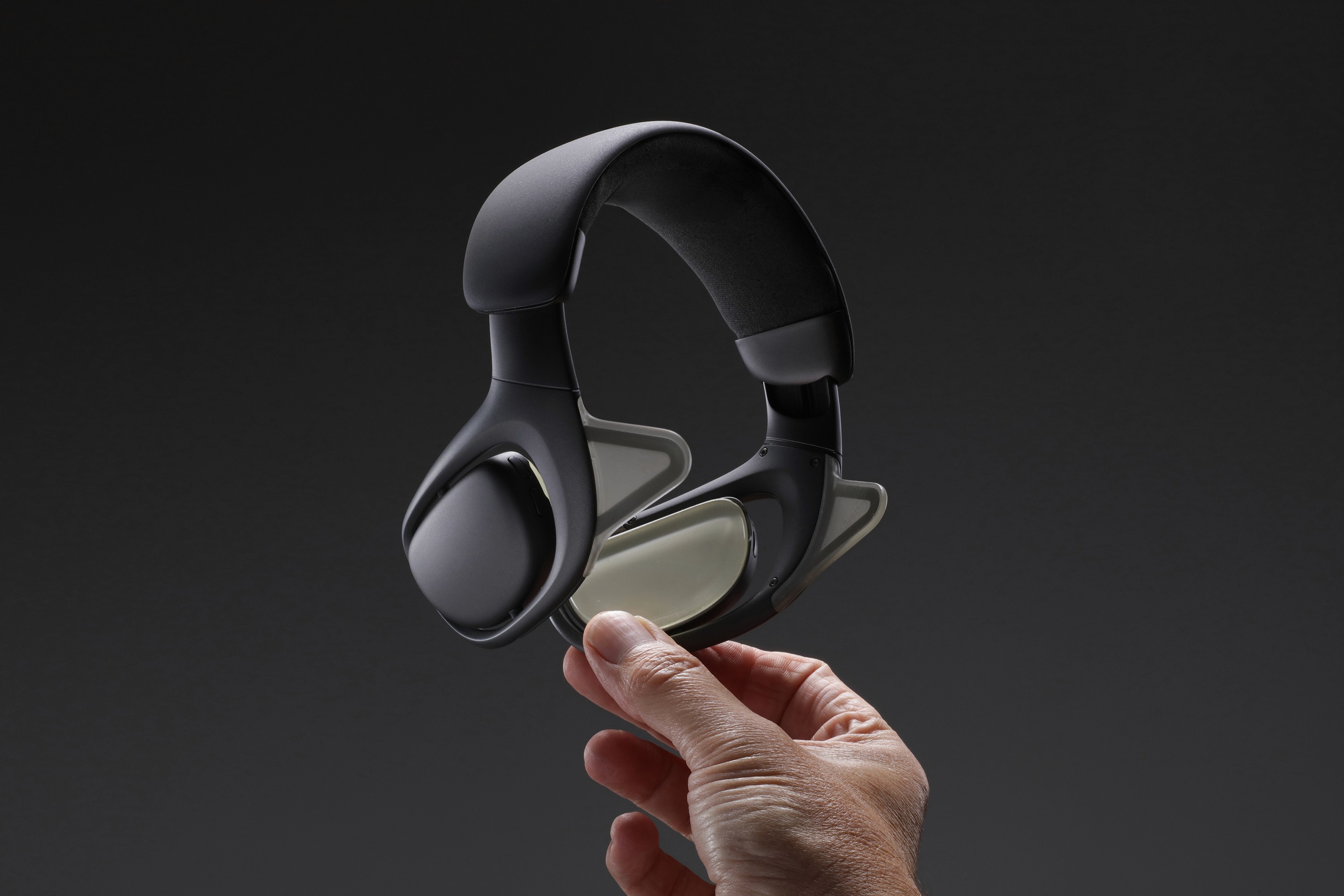 Close-up of the Nudge wearable held in hand, showing the grey CMF and rear wing structure