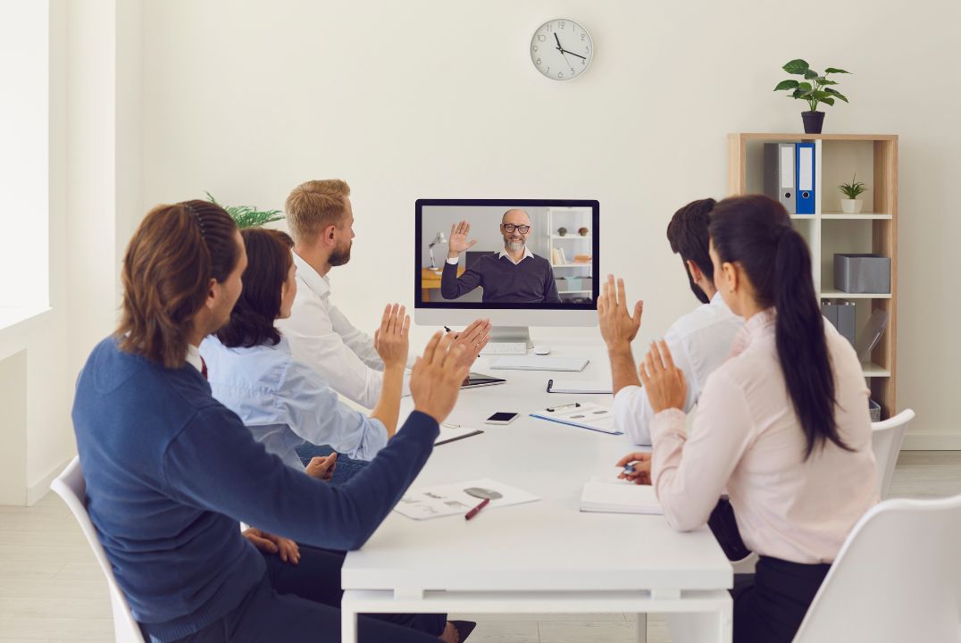 Team warmly greeting new colleague through a video conference call, showcasing virtual welcome and online employee integration strategies.