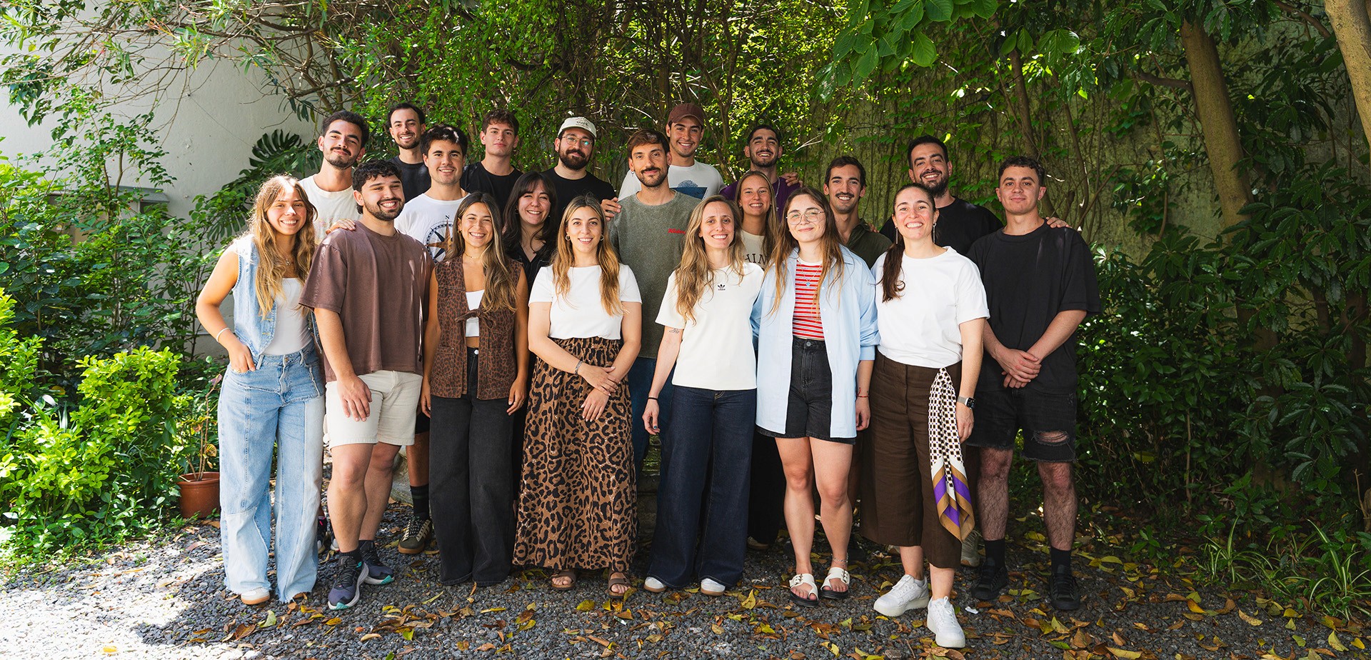 Retrato grupal del equipo, en un patio, en la sombra de varios árboles