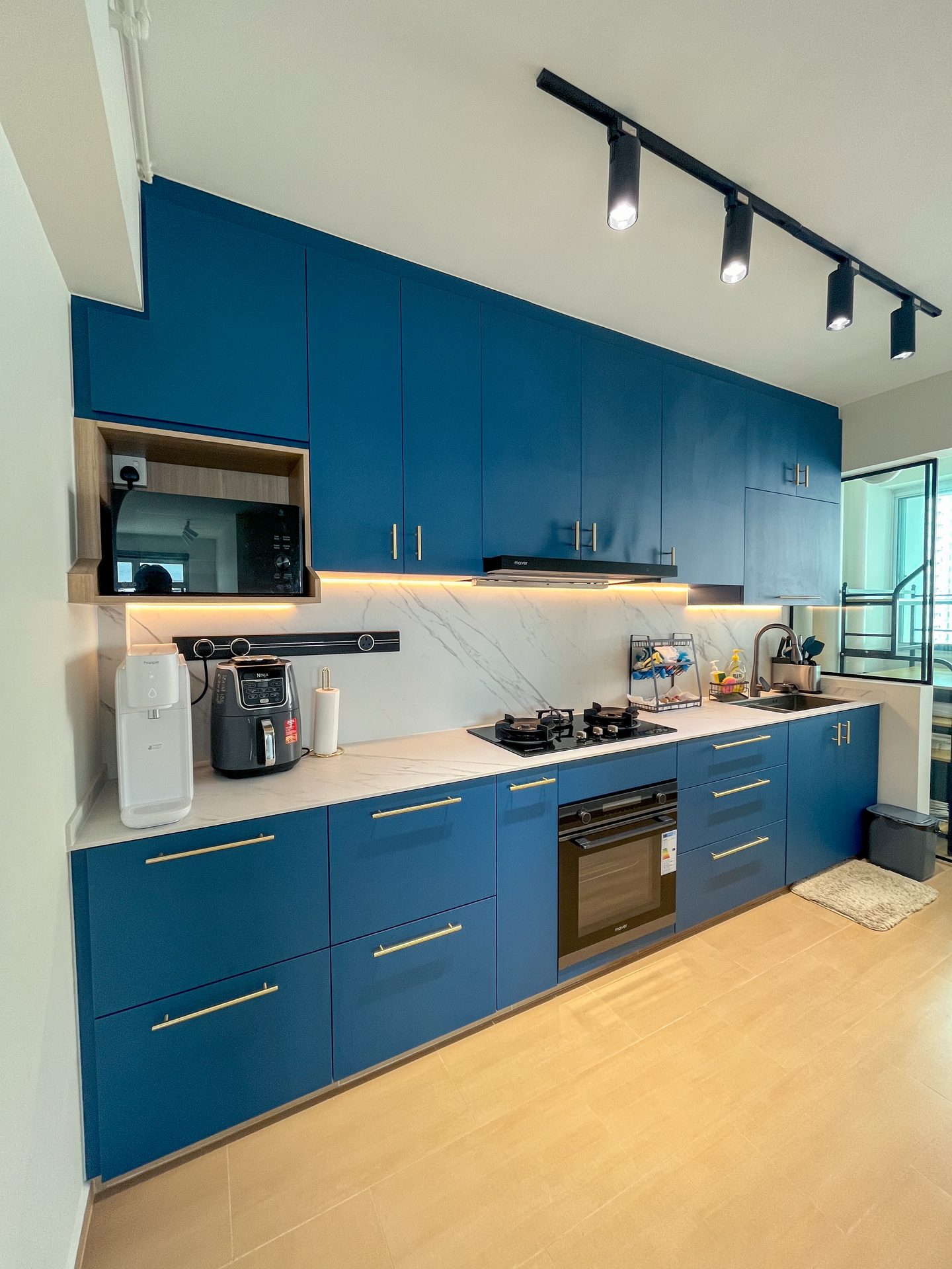 Warm sandy floor tiles from Soon Bee Huat complement dark blue kitchen cabinets