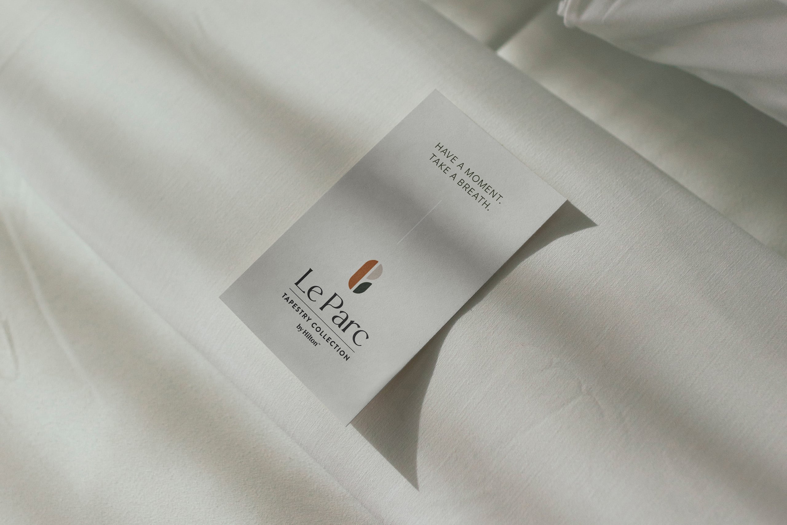A Le Parc branded card laying on a hotel bed