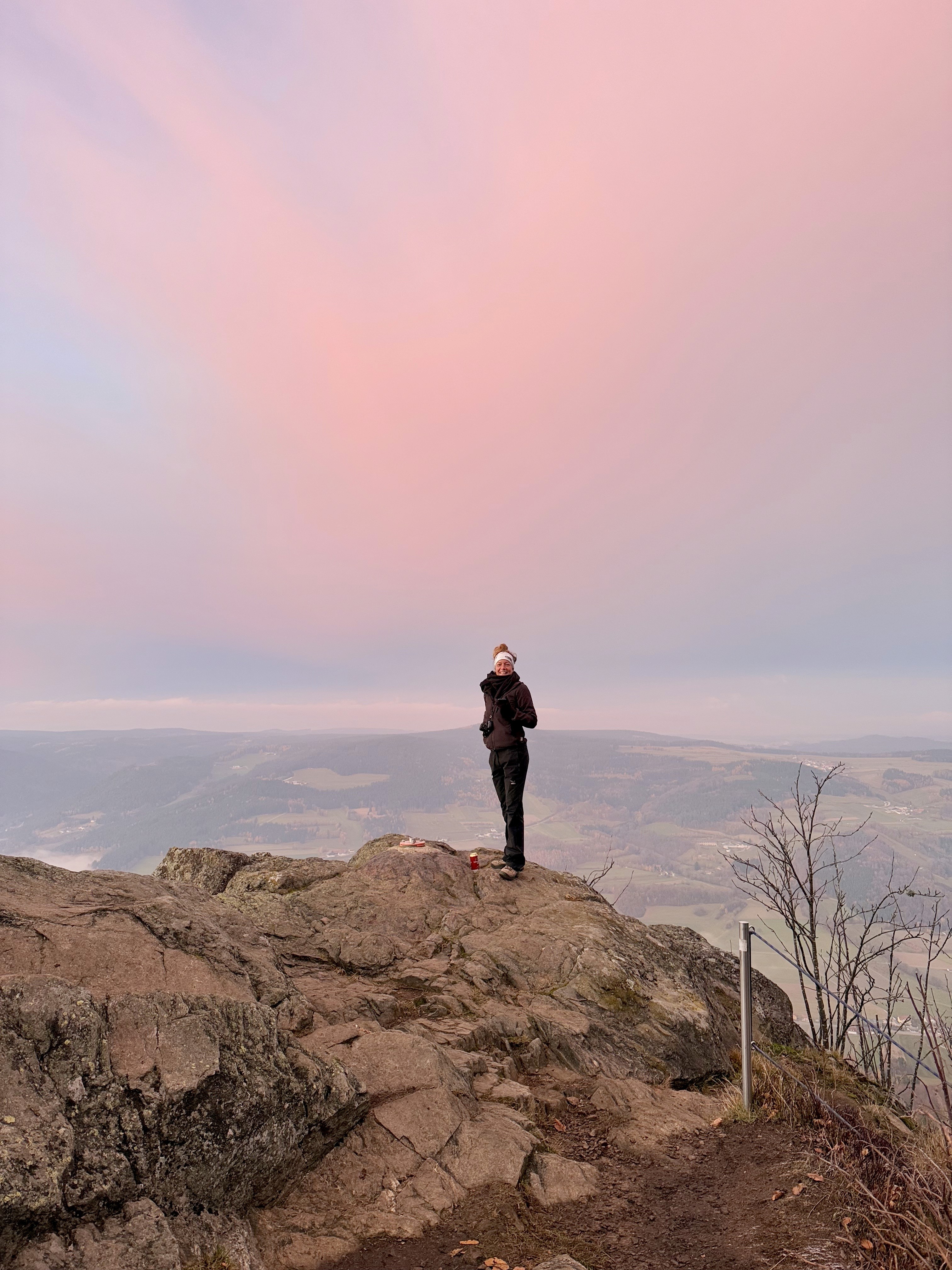 Sonnenuntergang am Berg, der Himmel ist rosarot, auf der Bergkante steht Manuela Schlager