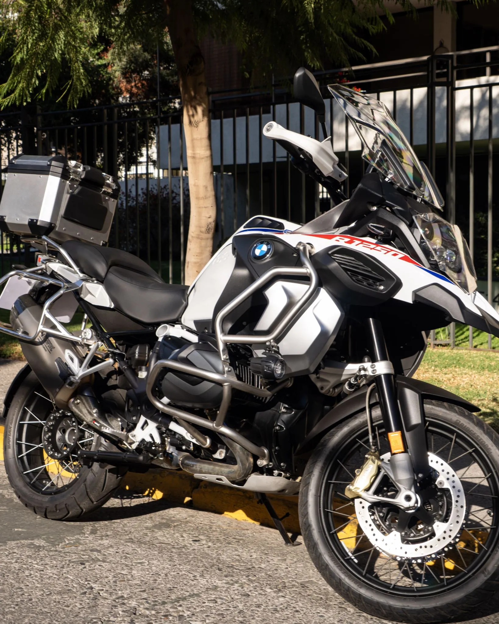 BMW R 1250 GS Adventure estacionada de lado con defensas metálicas, parabrisas alto y maleta trasera