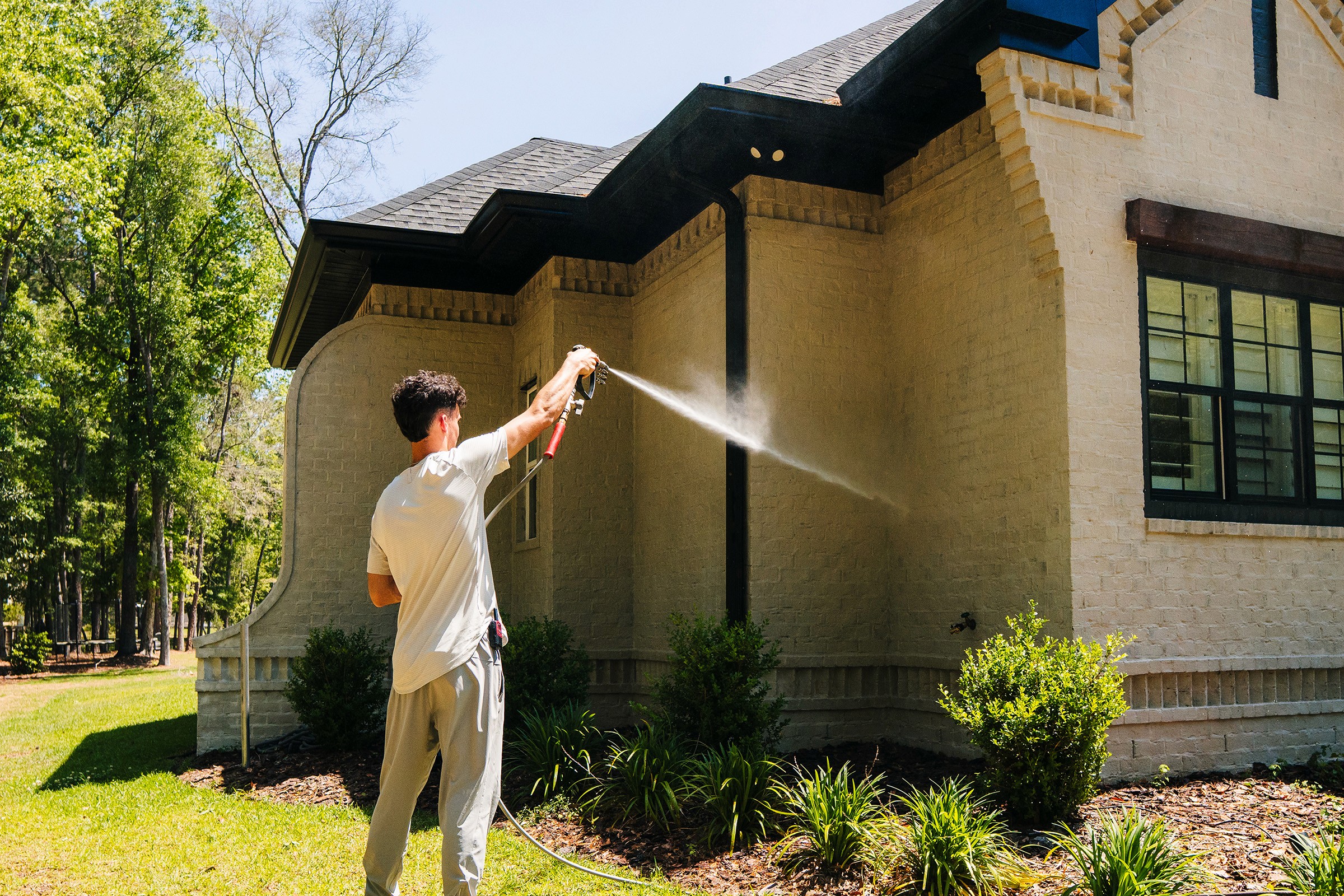 Worker washing side of house