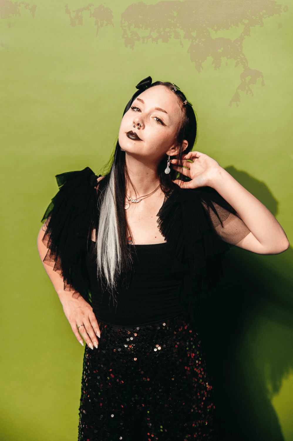 Sophie Liffick with So Curious Co poses in a sparkly black dress on a green background