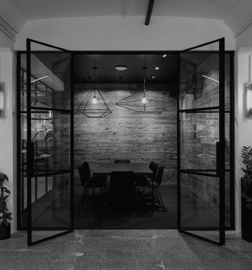 A modern black double door opens into a stylish indoor space with decorative features and warm lighting.
