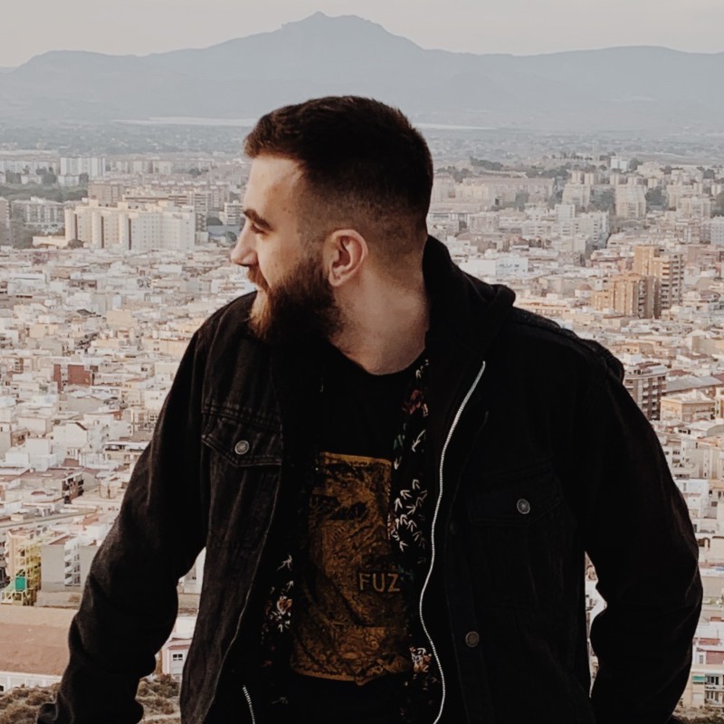 A thoughtful young person with dark hair gazes to the side, captured in soft black and white lighting.