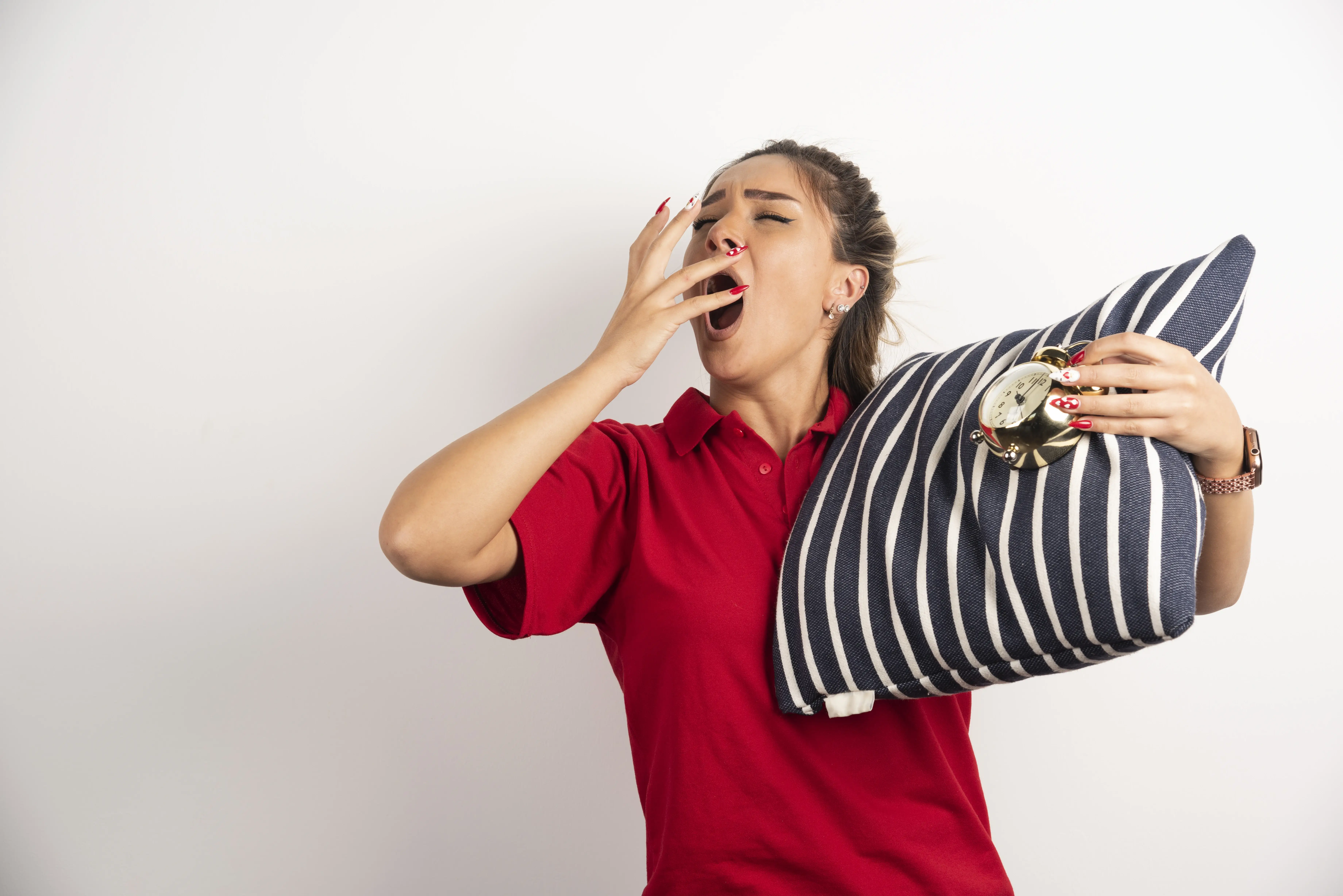 Persona bostezando mientras sostiene una almohada, representando el cansancio y la fatiga.