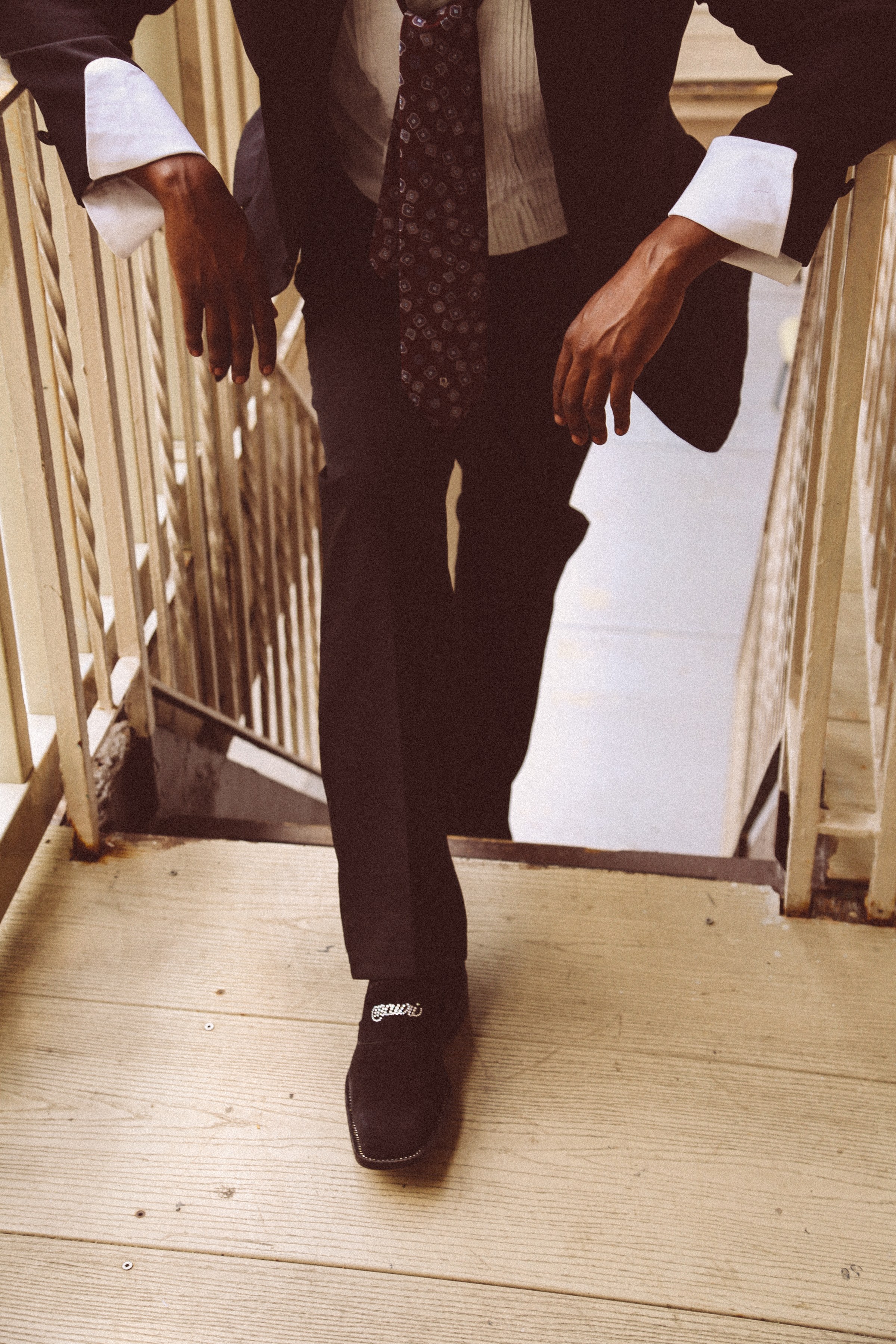 Man in tailored suit and tie stepping down a staircase