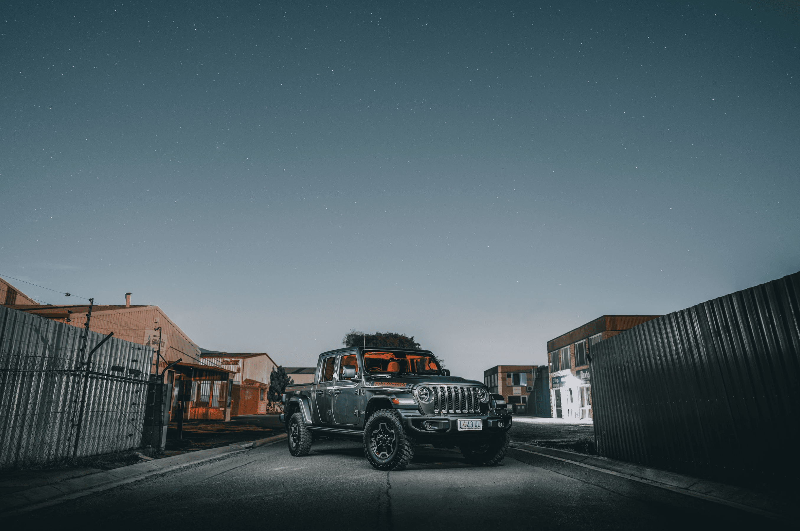 Silhouette of a filmmaker with a camera on a tripod in a dimly lit alley, bathed in orange light and mist, creating a moody, cinematic atmosphere.