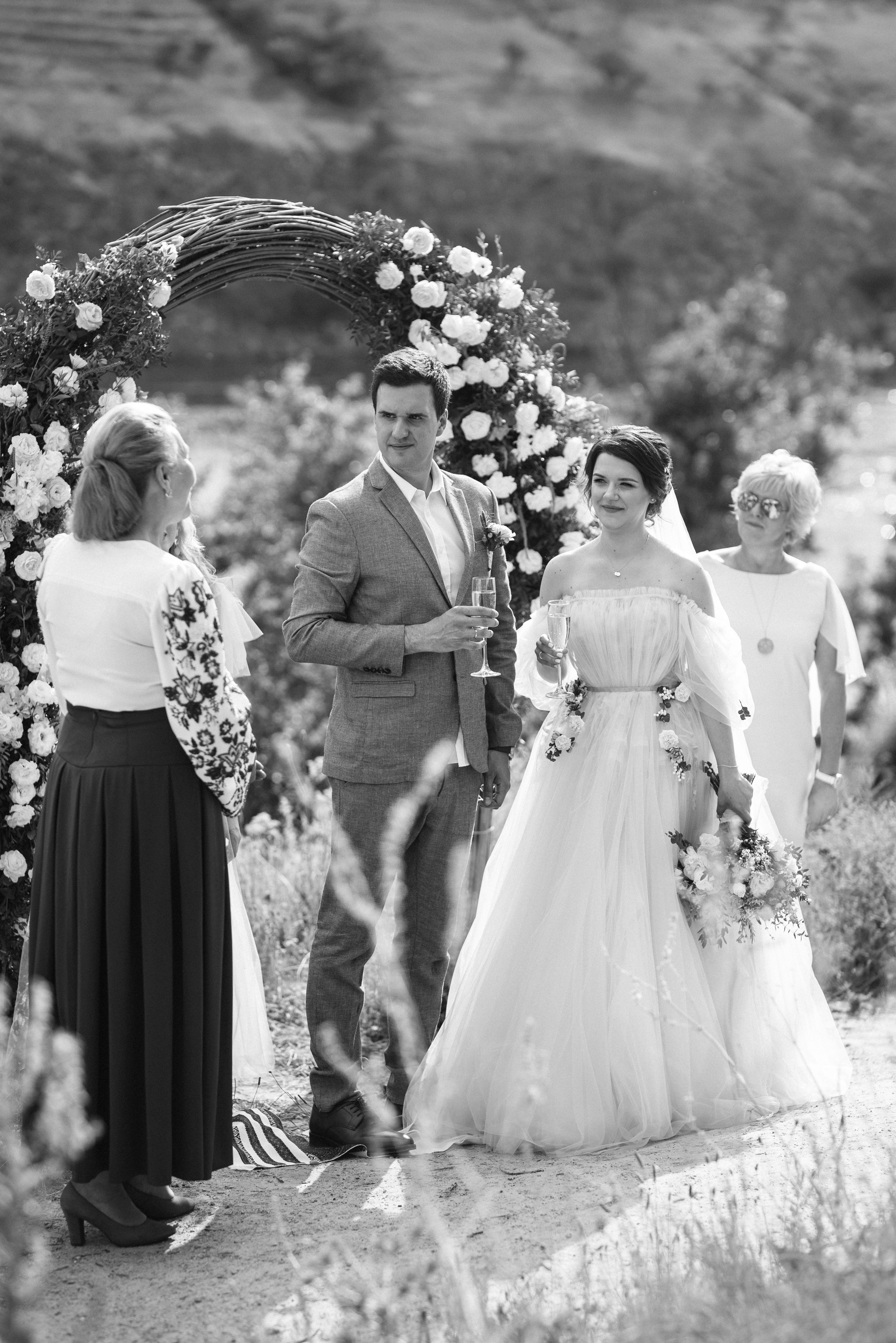 Bride and groom walking under floral arch after outdoor wedding ceremony