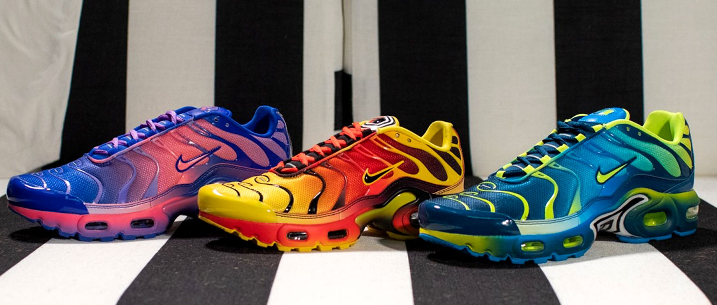 Three pairs of gradient Nike Air Max Plus sneakers lined up against a black-and-white striped backdrop
