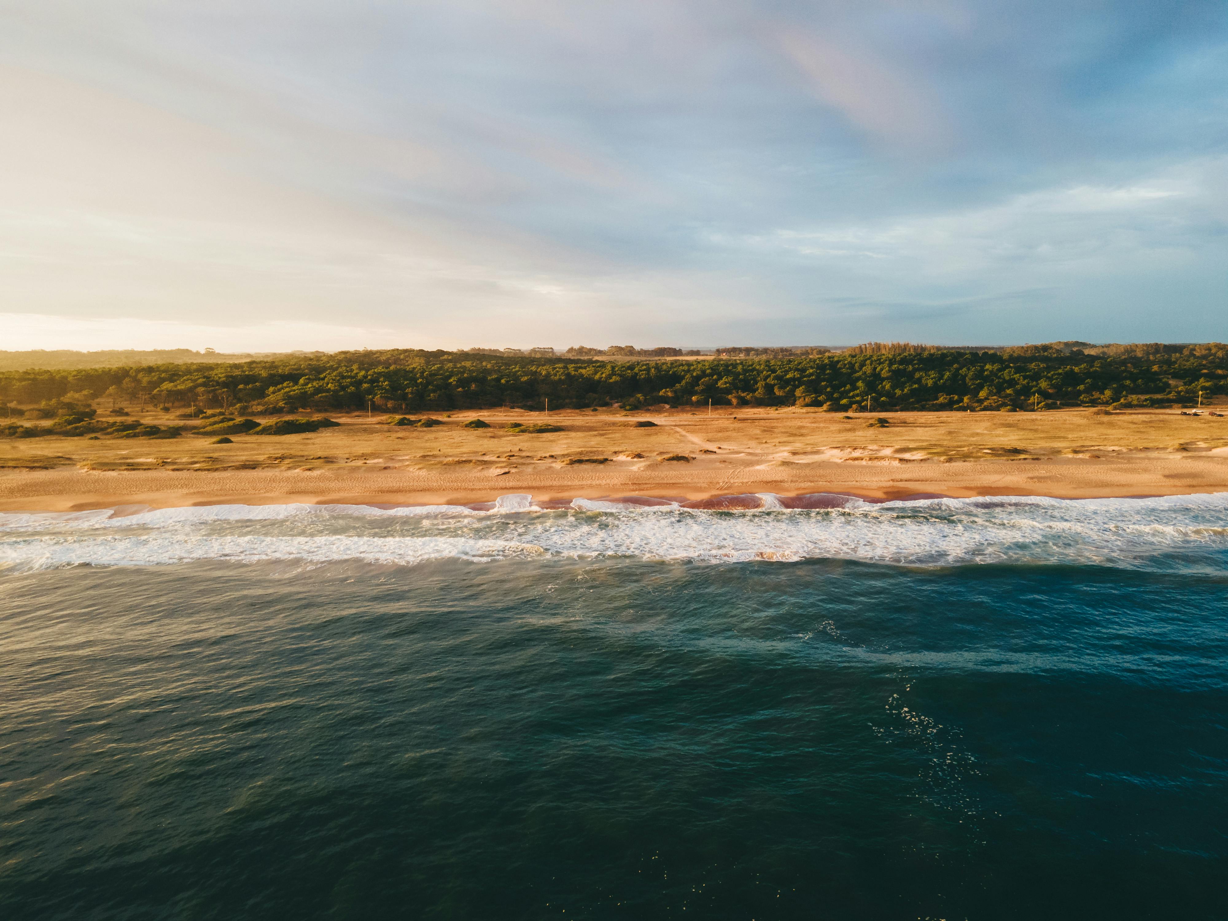Vista aérea de una playa y dunas en la costa de Uruguay, destino costero para planificar con una aplicación de turismo.