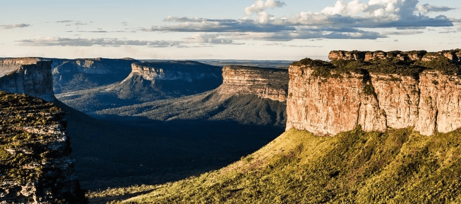 green and brown mountains near body of water under white clouds and blue sky during daytime