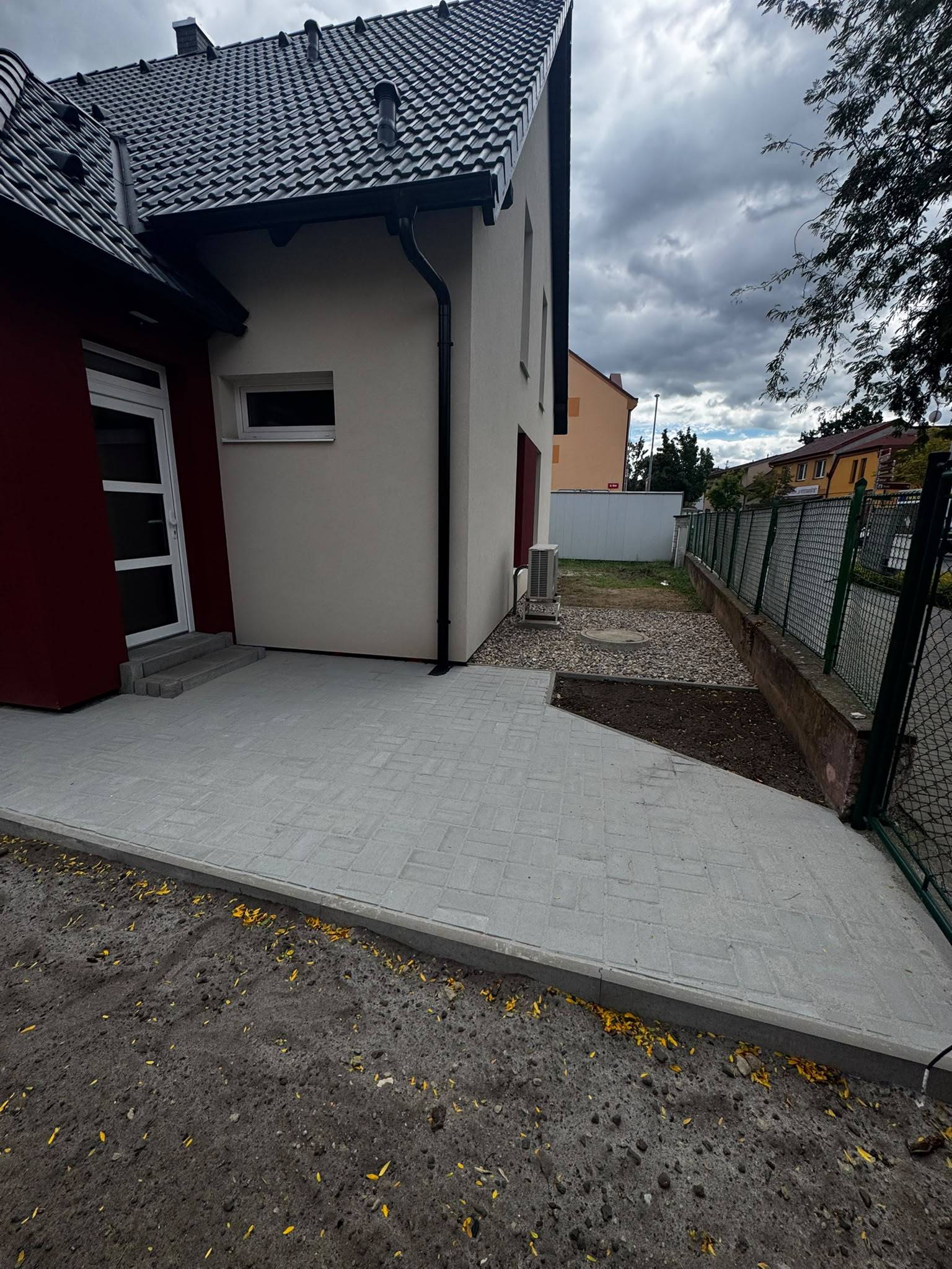 Dlážděný chodník okolo domu s obrubníky