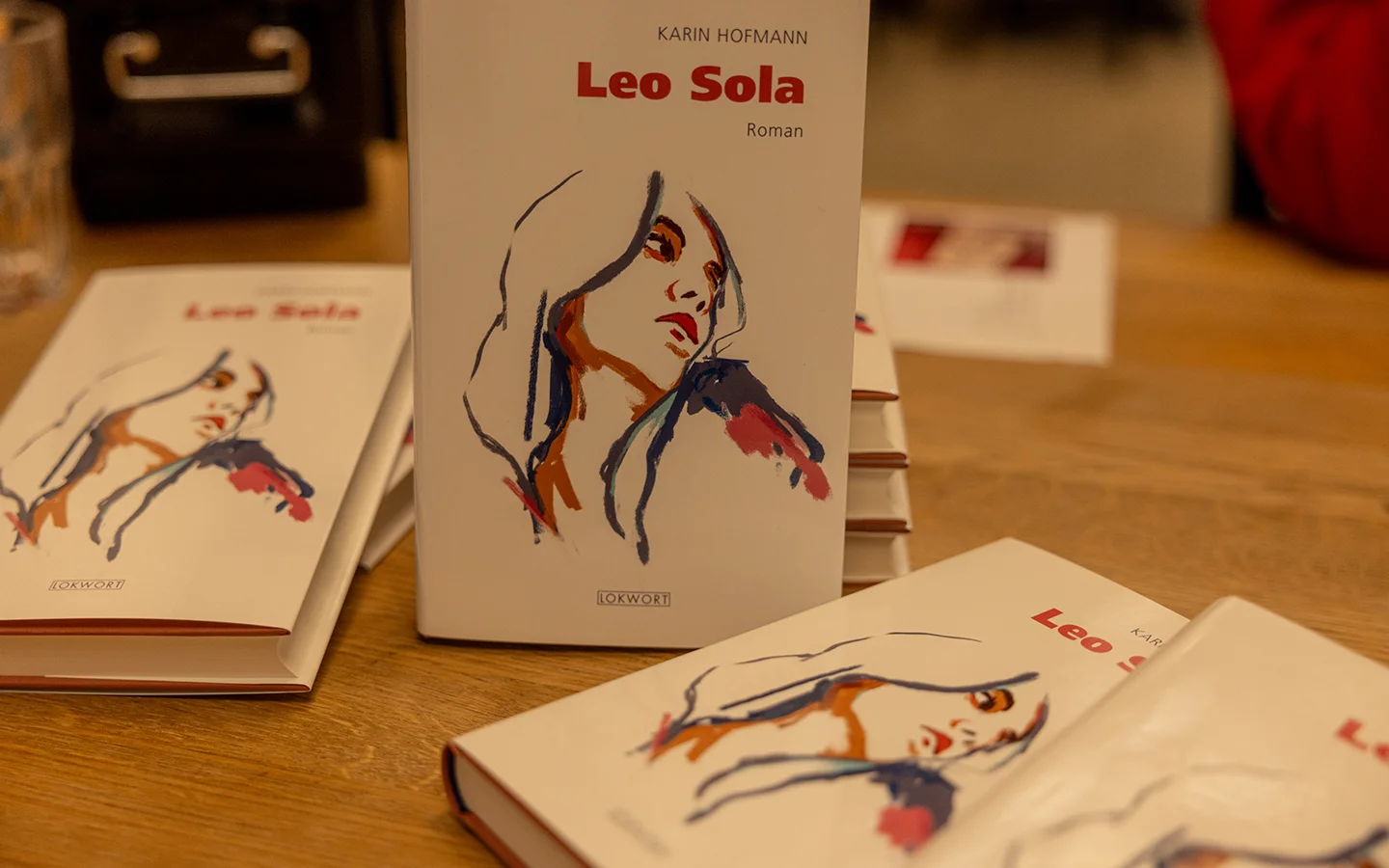 A closed pink lotus flower bud behind a large leaf.