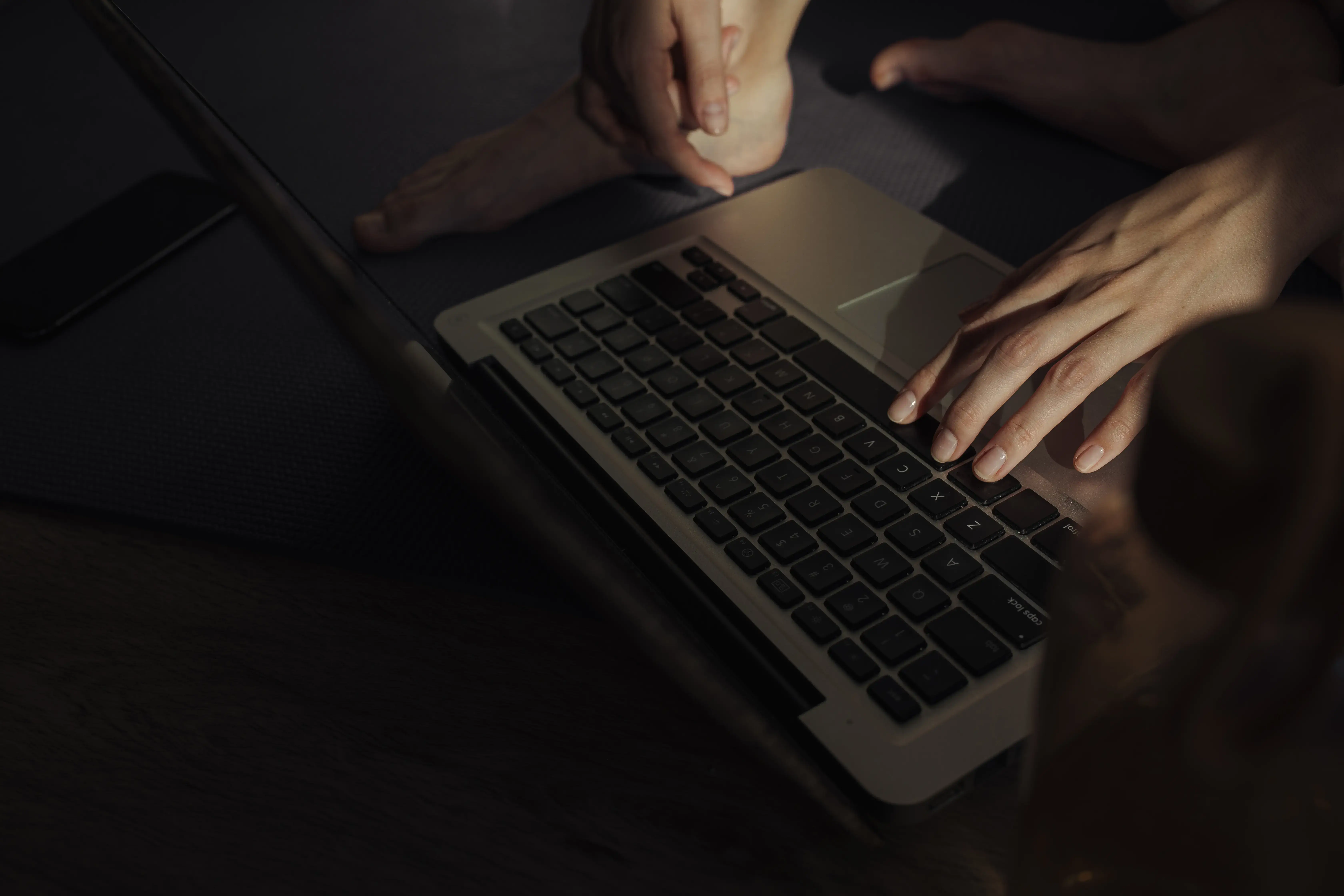 Person using a laptop in low light.