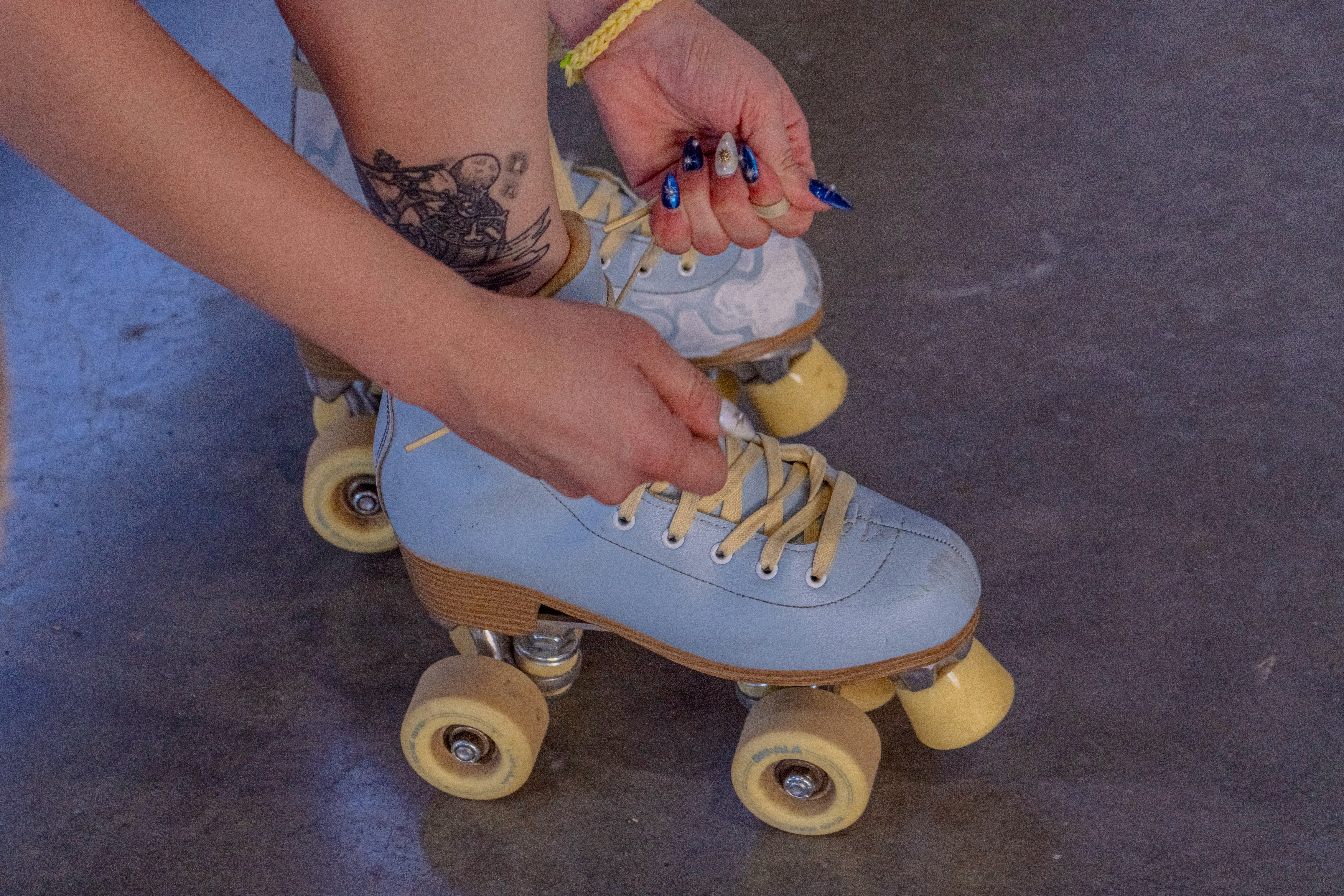 Someone is tying the laces on their roller skates.