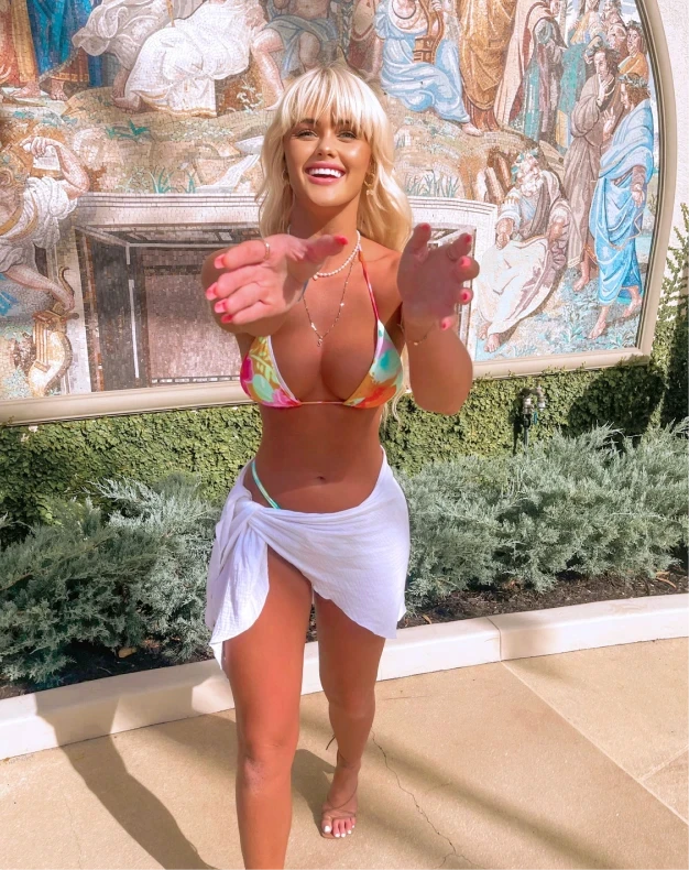 Topless waitress Lola posing outdoors in a colourful bikini top and white wrap skirt for an Hourglass Gold Coast promotional photo.