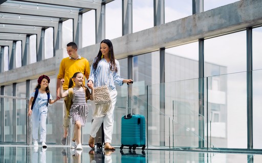 Obitelj prolazi kroz terminal zračne luke s prtljagom.