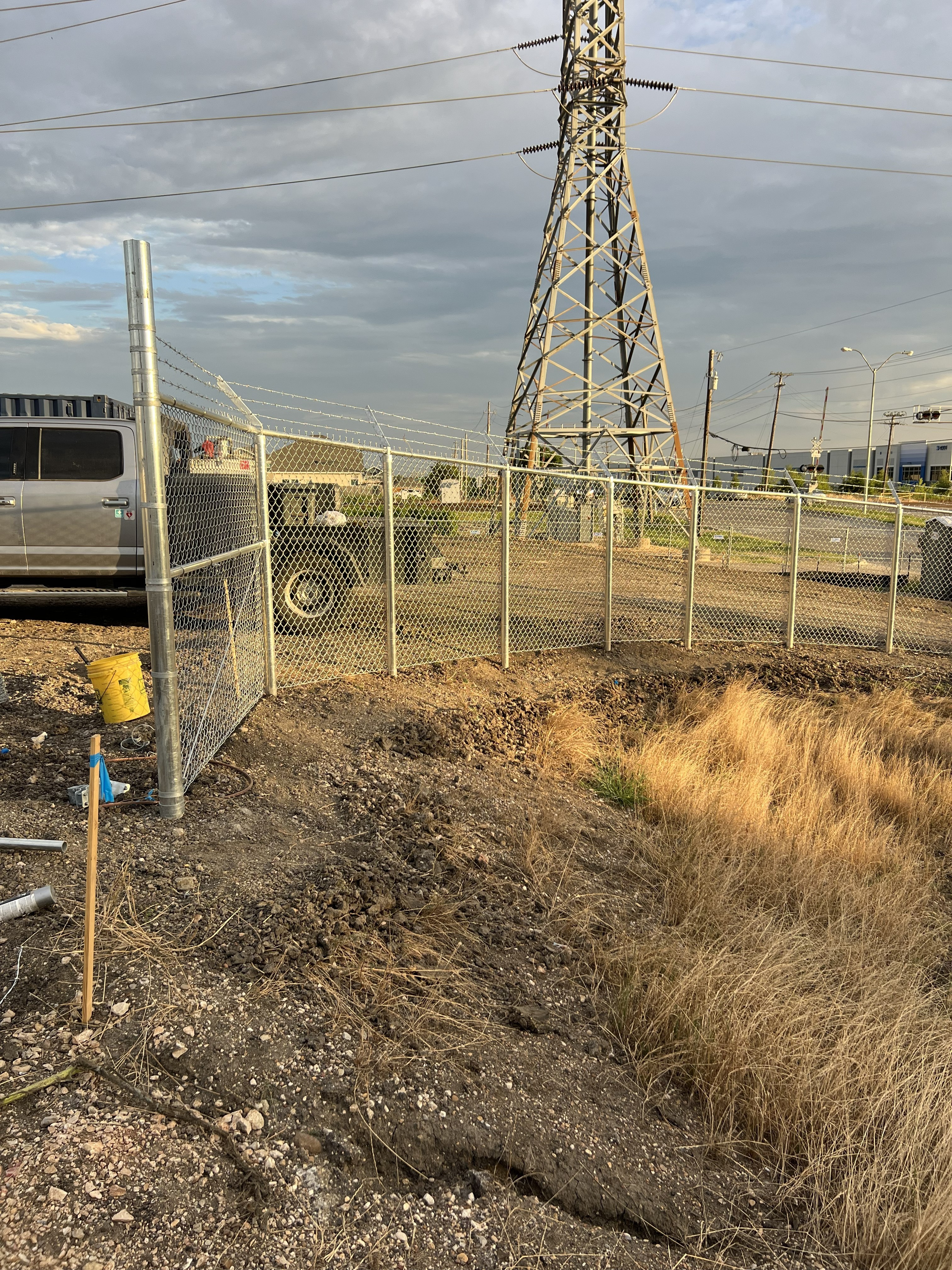 a dirt road next to a chain link fence