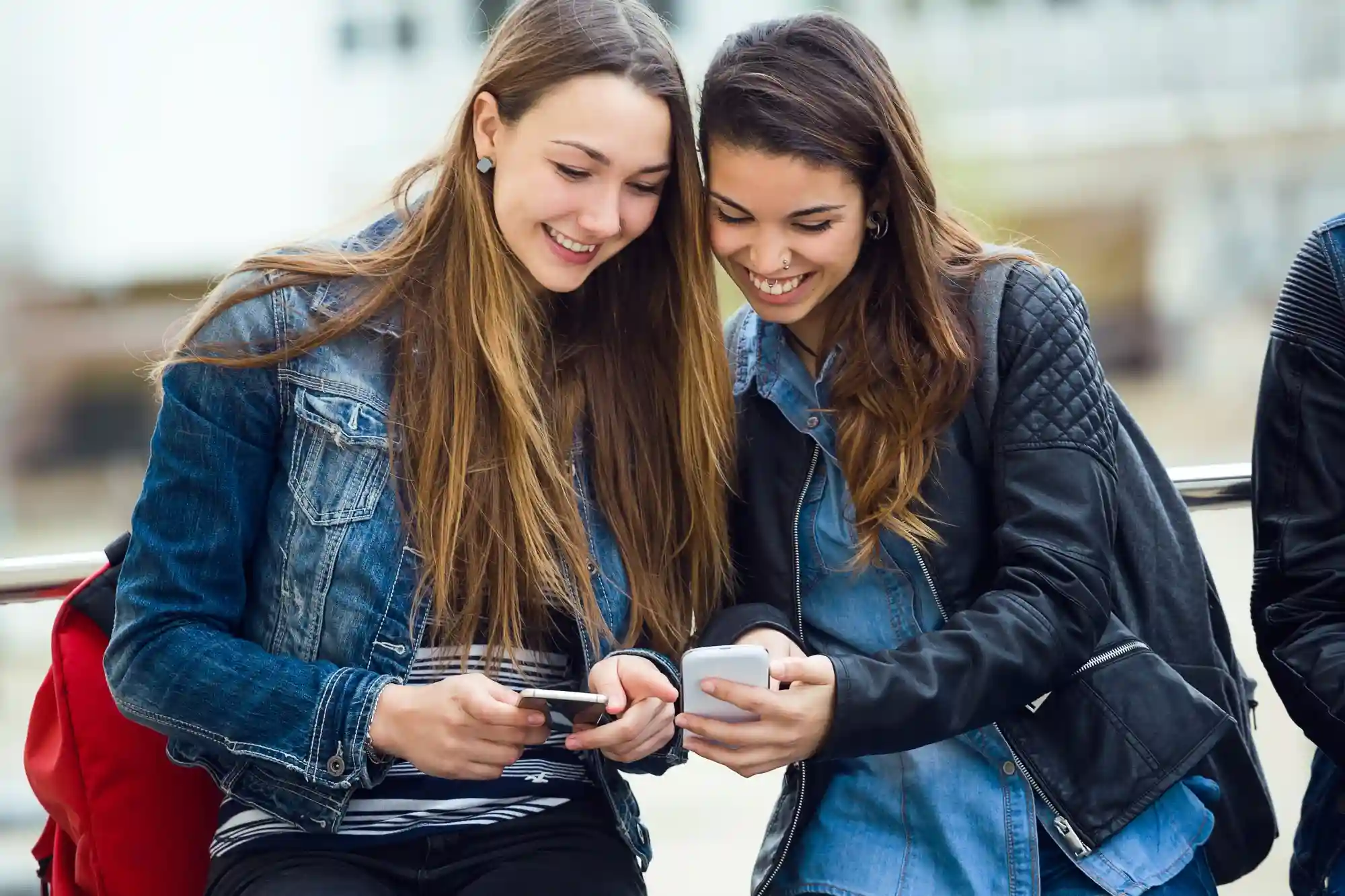 Teenage girls using a smartphone, representing the users who will be removed from platforms by Australia's new law.
