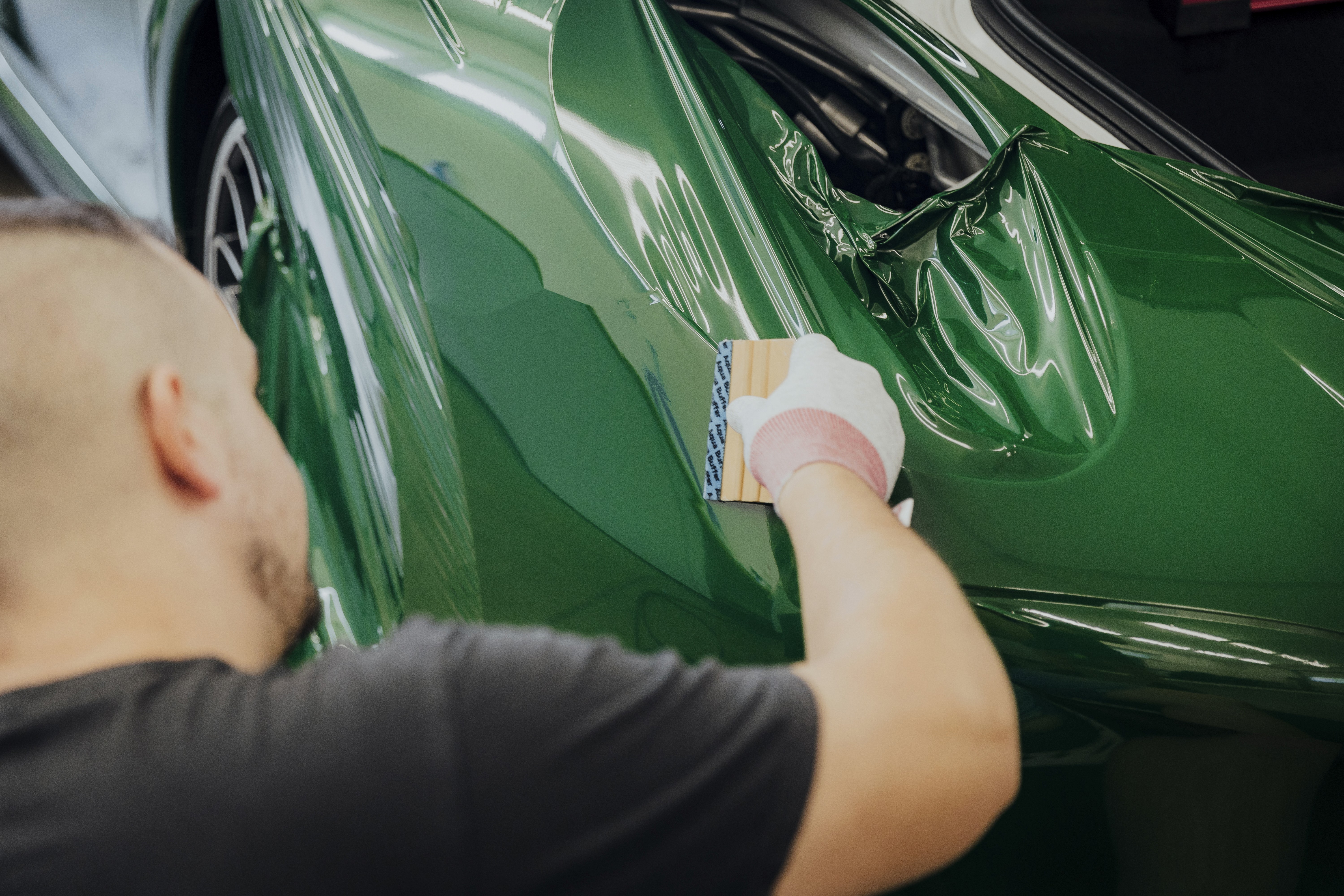 Közeli kép a zöld autófólia buborékmentes felhelyezéséről és simításáról a Nortek csapatától.