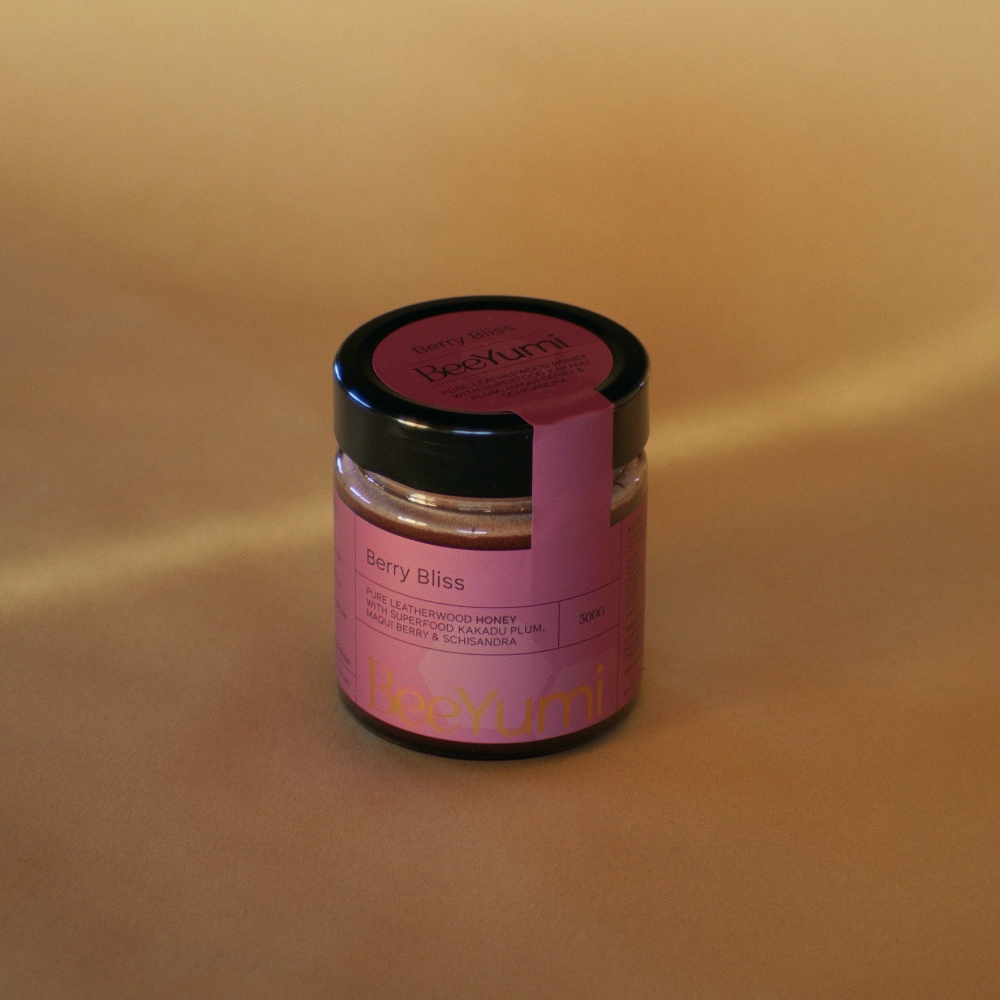 Jar of BeeYum Berry Bliss honey on a beige background