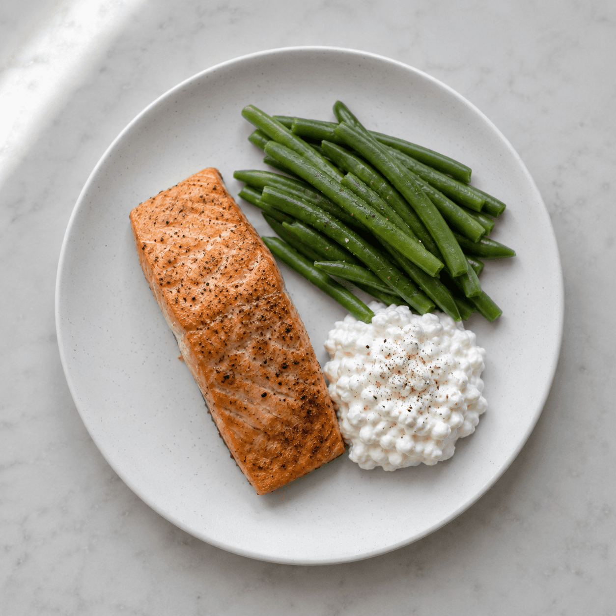 Small portioned plate with salmon, green beans and cottage cheese illustrating high-protein meal for GLP-1 medication users